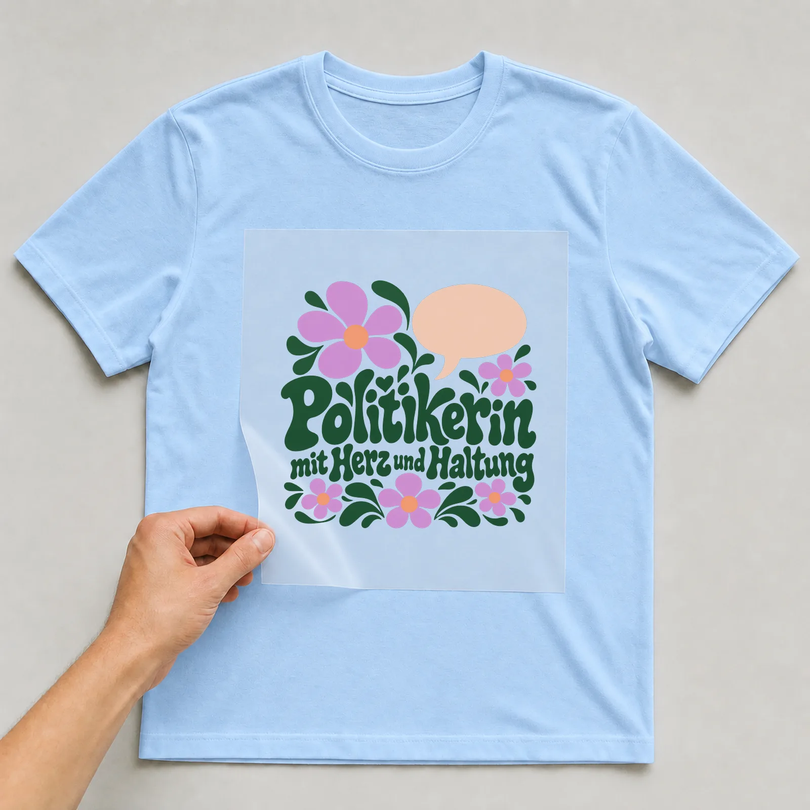Bügelbild „Politikerin mit Herz und Haltung“ auf hellblauem T-Shirt, Folie wird aufgelegt