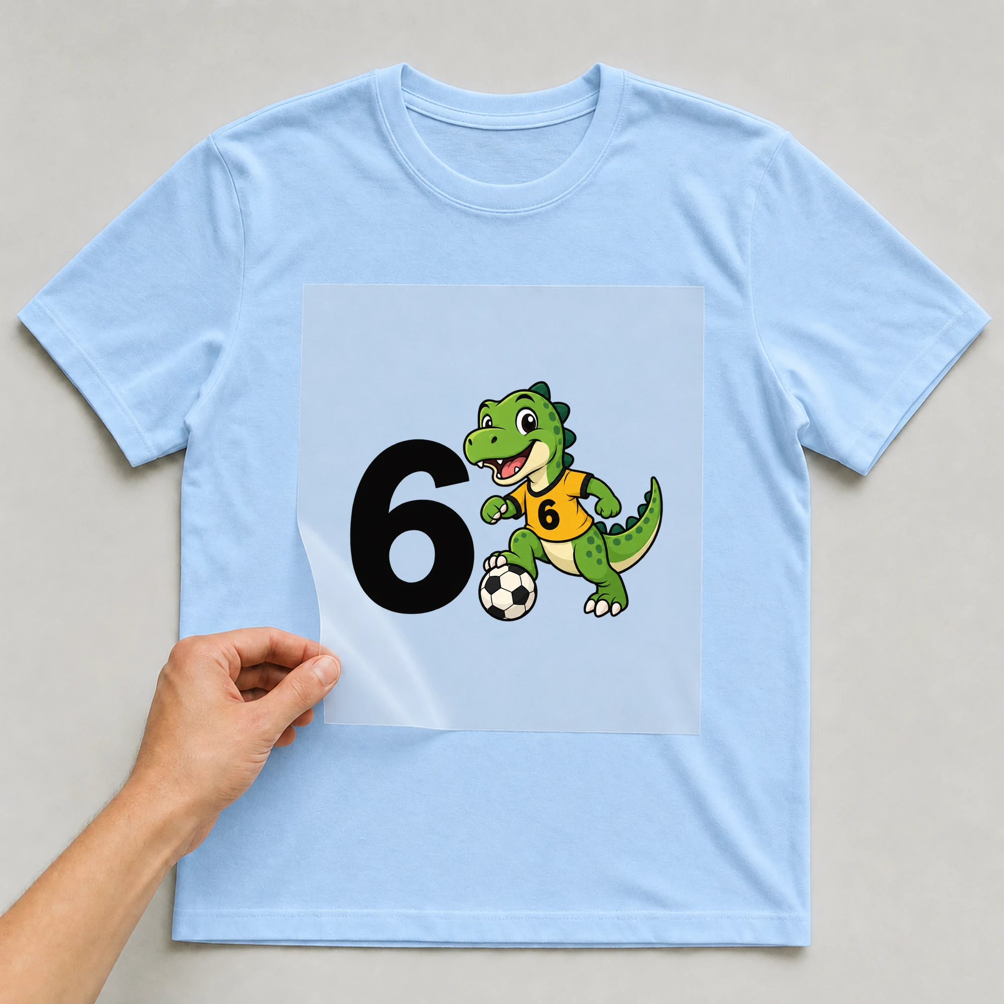 Bügelbild „6 6“ auf babyblauem T-Shirt, Folie wird aufgelegt