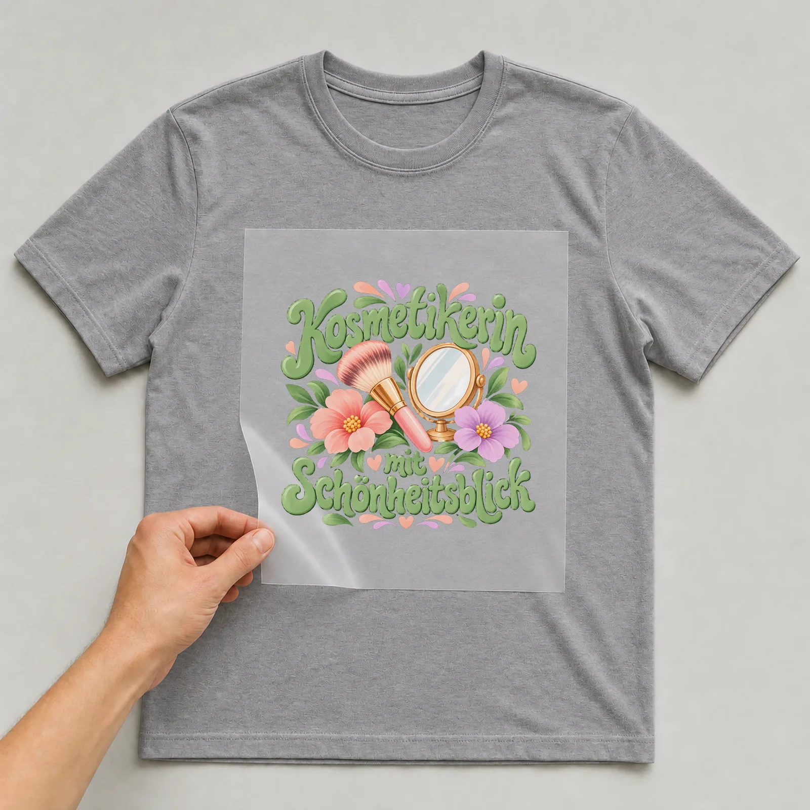Bügelbild „Kosmetikerin mit Schönheitsblick“ auf grauem T-Shirt, Folie wird aufgelegt