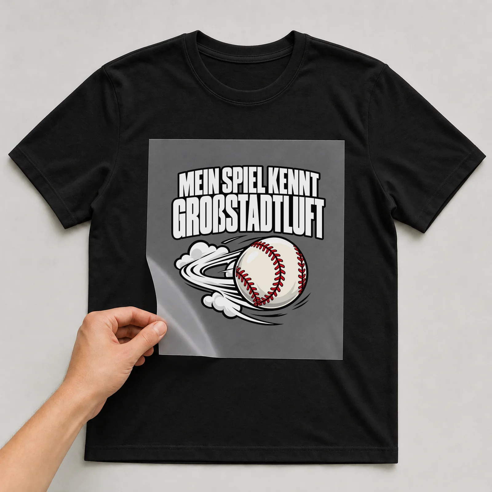 Bügelbild „Mein spiel kennt Großstadtluft“ auf schwarzem T-Shirt, Folie wird aufgelegt