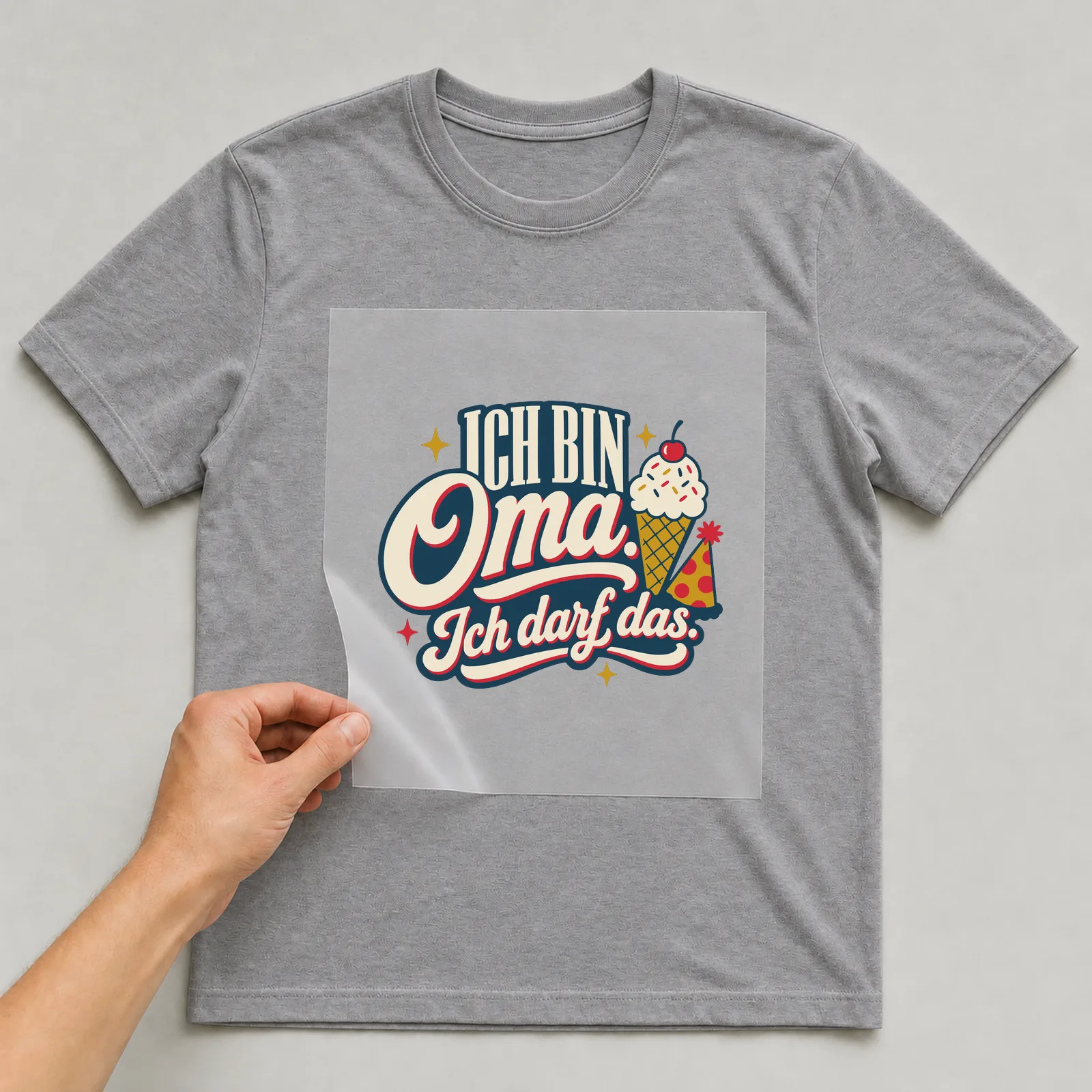Bügelbild Ich bin Oma. Ich darf das. auf grauem T-Shirt, Folie wird aufgelegt