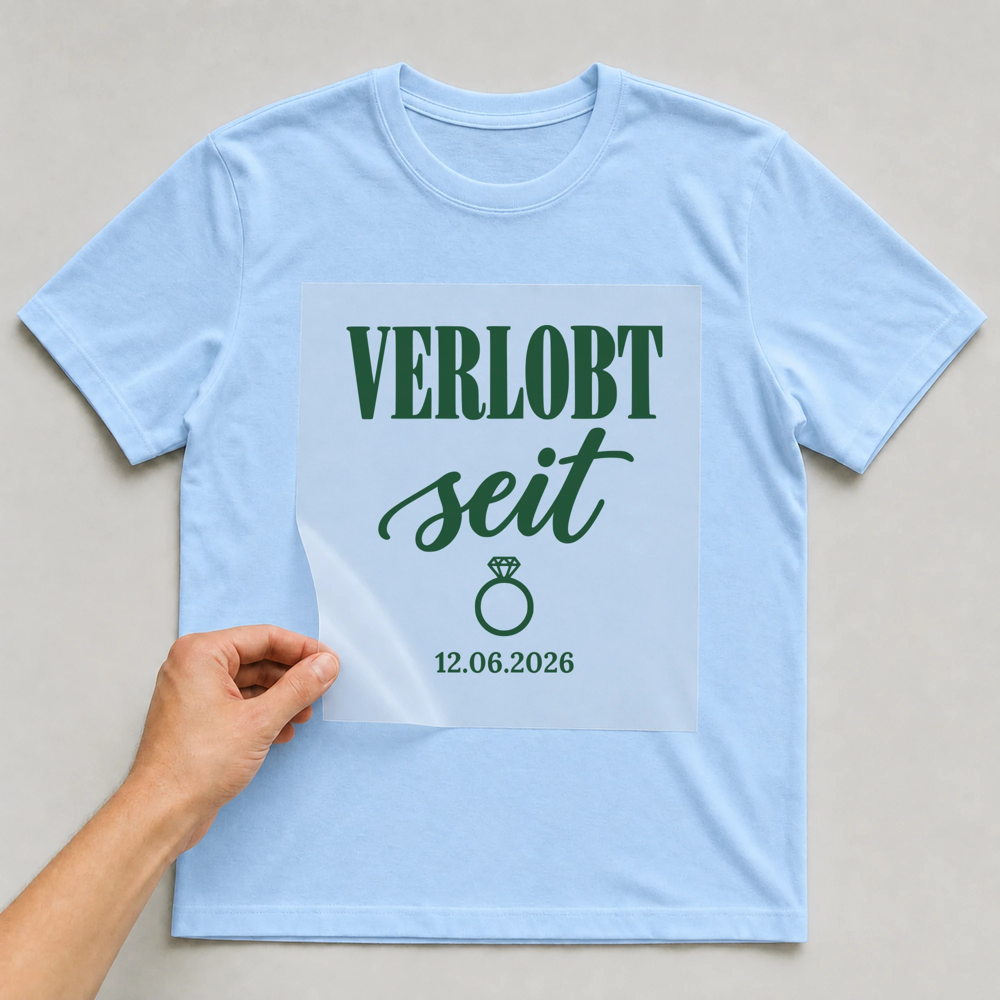 Bügelbild Verlobt seit mit Datum auf hellblauem T-Shirt, Folie wird aufgelegt