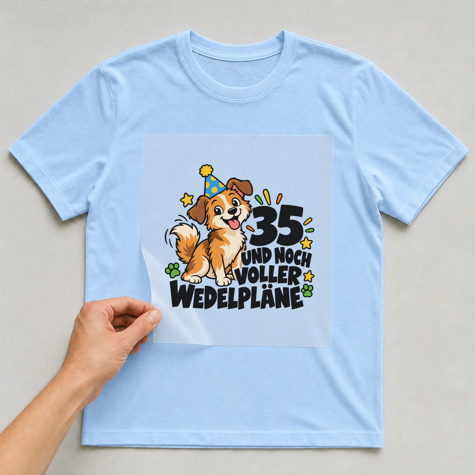 Bügelbild „35 Und noch voller Wedelpläne“ auf hellblauem T-Shirt, Folie wird aufgelegt