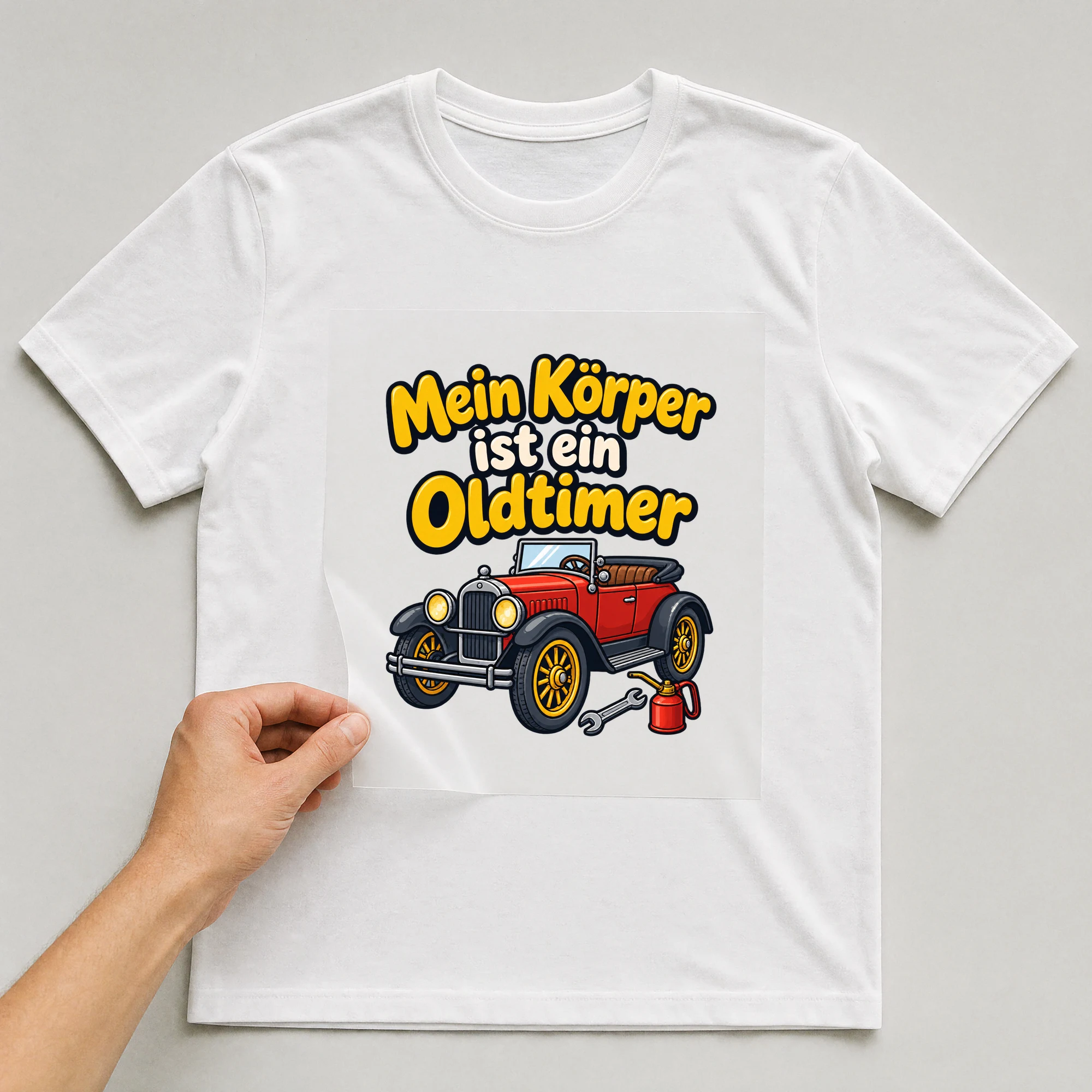 Bügelbild „Mein Körper ist ein Oldtimer“ auf weißem T-Shirt, Folie wird aufgelegt