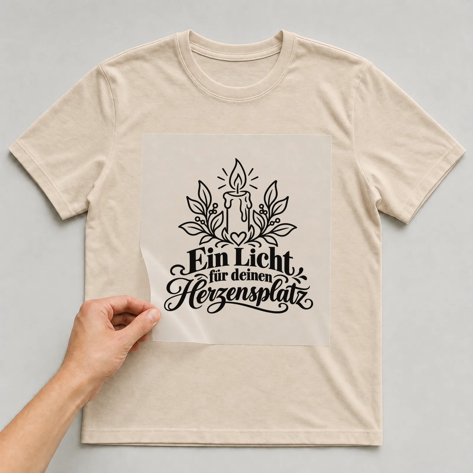 Bügelbild „Ein Licht für deinen Herzensplatz“ auf beigem T-Shirt, Folie wird aufgelegt