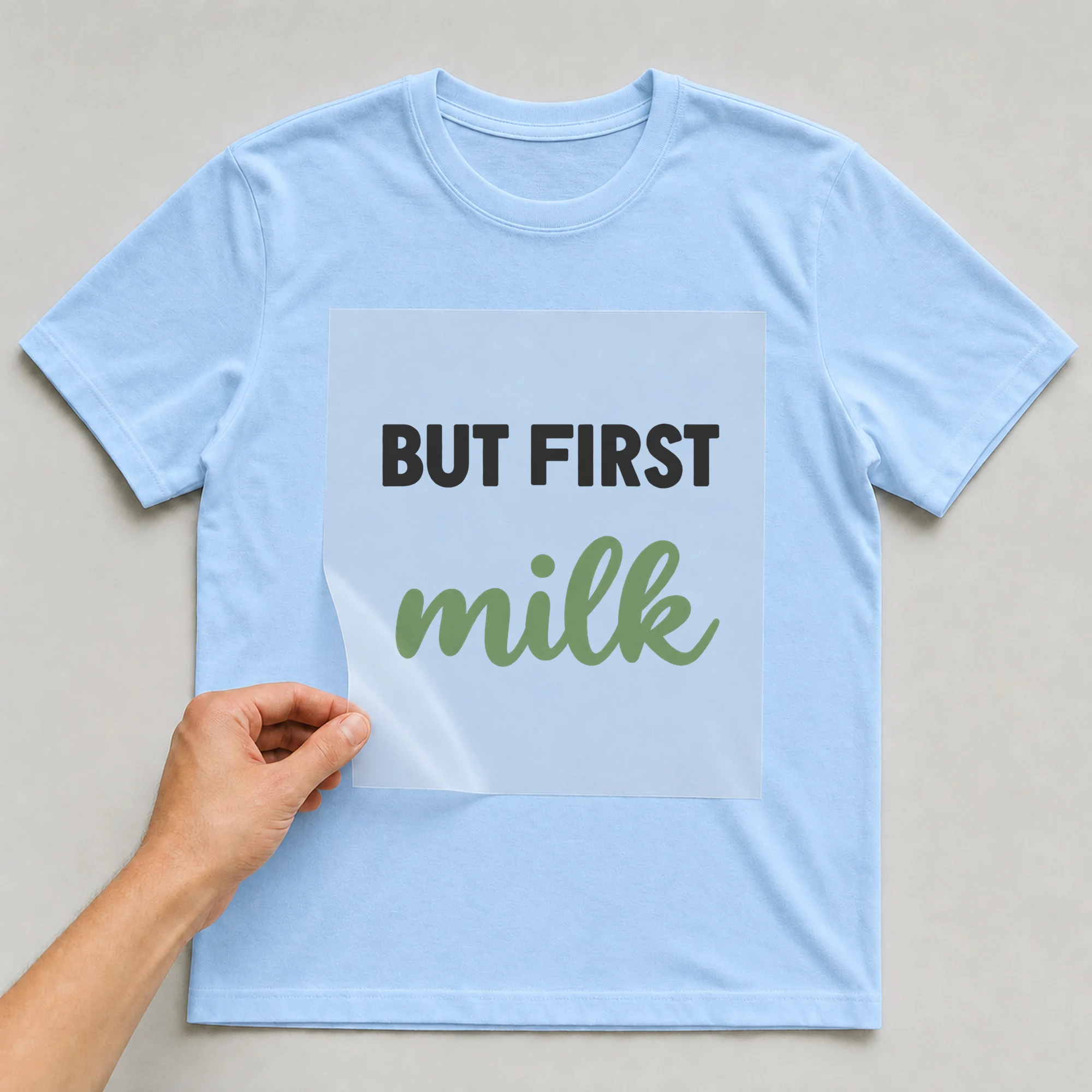 Bügelbild „BUT FIRST milk“ auf babyblauem T-Shirt, Folie wird aufgelegt