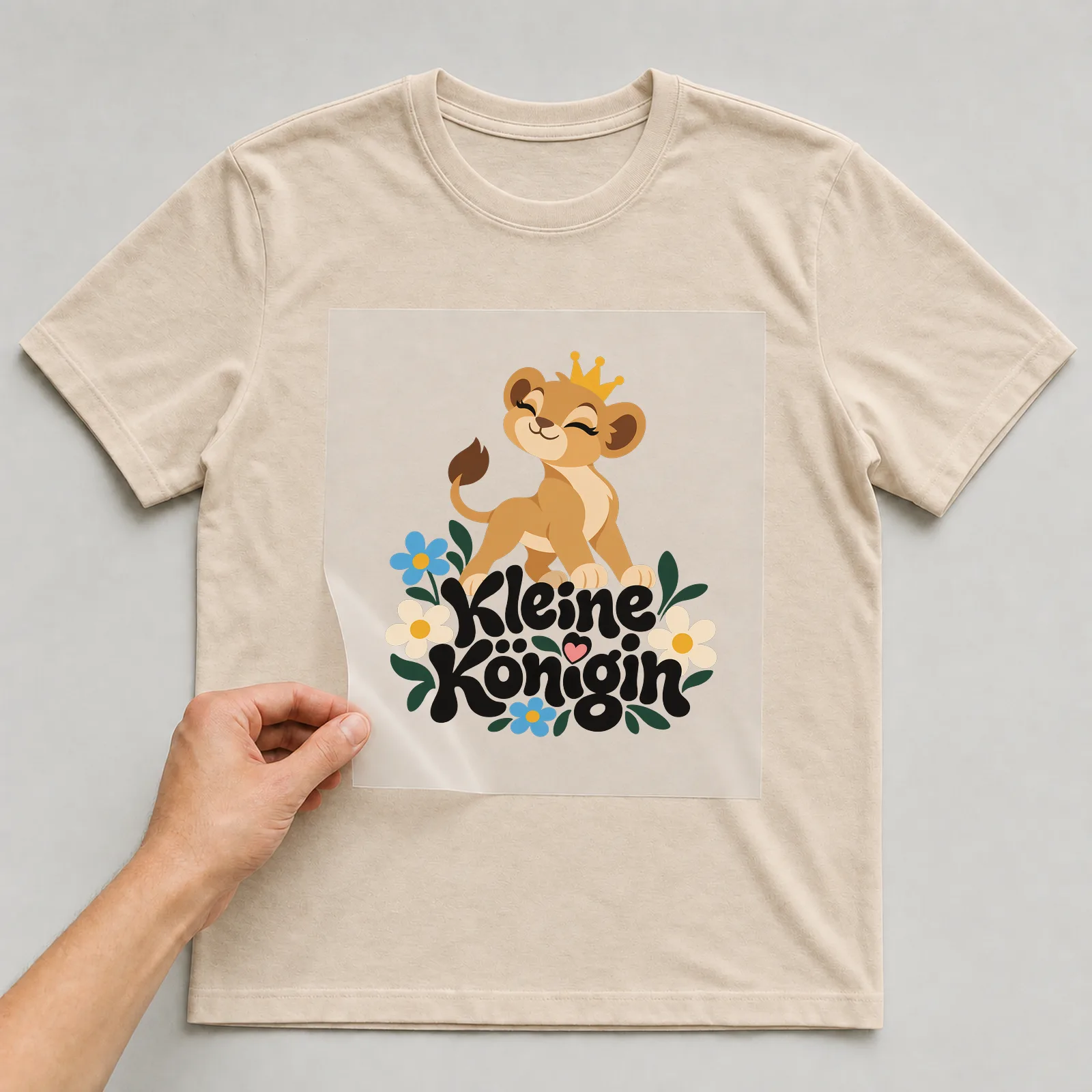 Bügelbild „Kleine Königin“ auf beigem T-Shirt, Folie wird aufgelegt