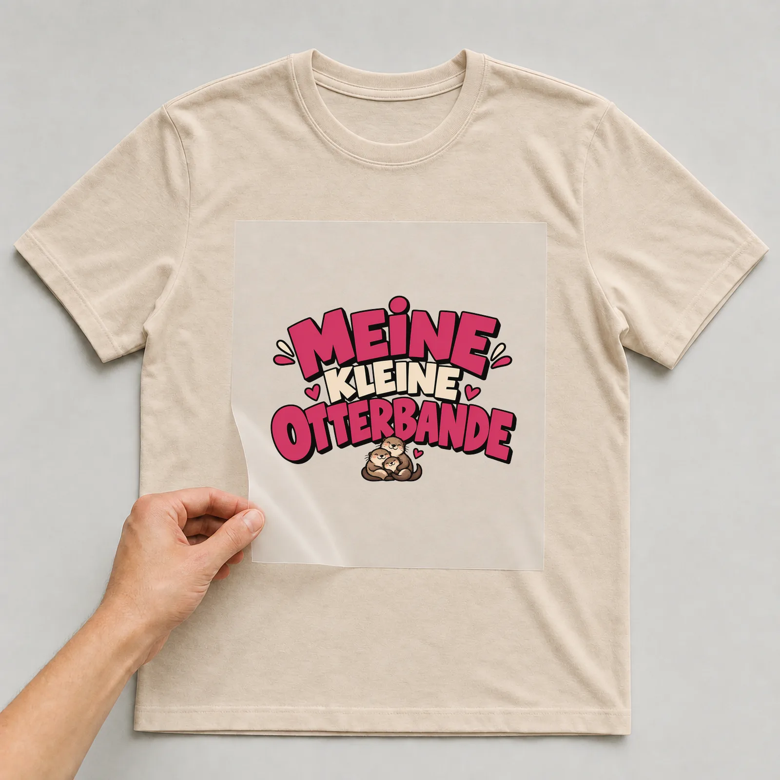 Bügelbild „Meine kleine Otterbande“ auf beigem T-Shirt, Folie wird aufgelegt