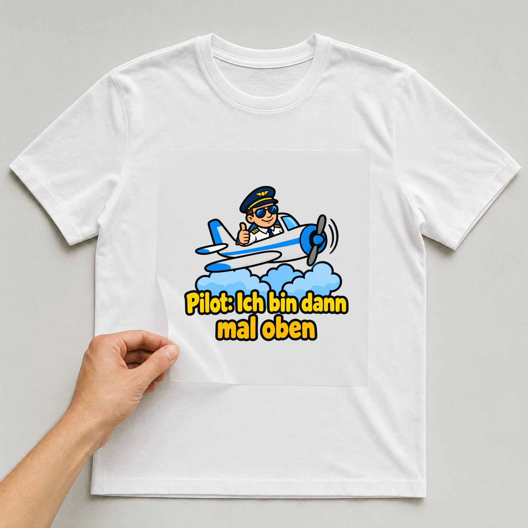 Bügelbild „Pilot: Ich bin dann mal oben“ auf weißem T-Shirt, Folie wird aufgelegt