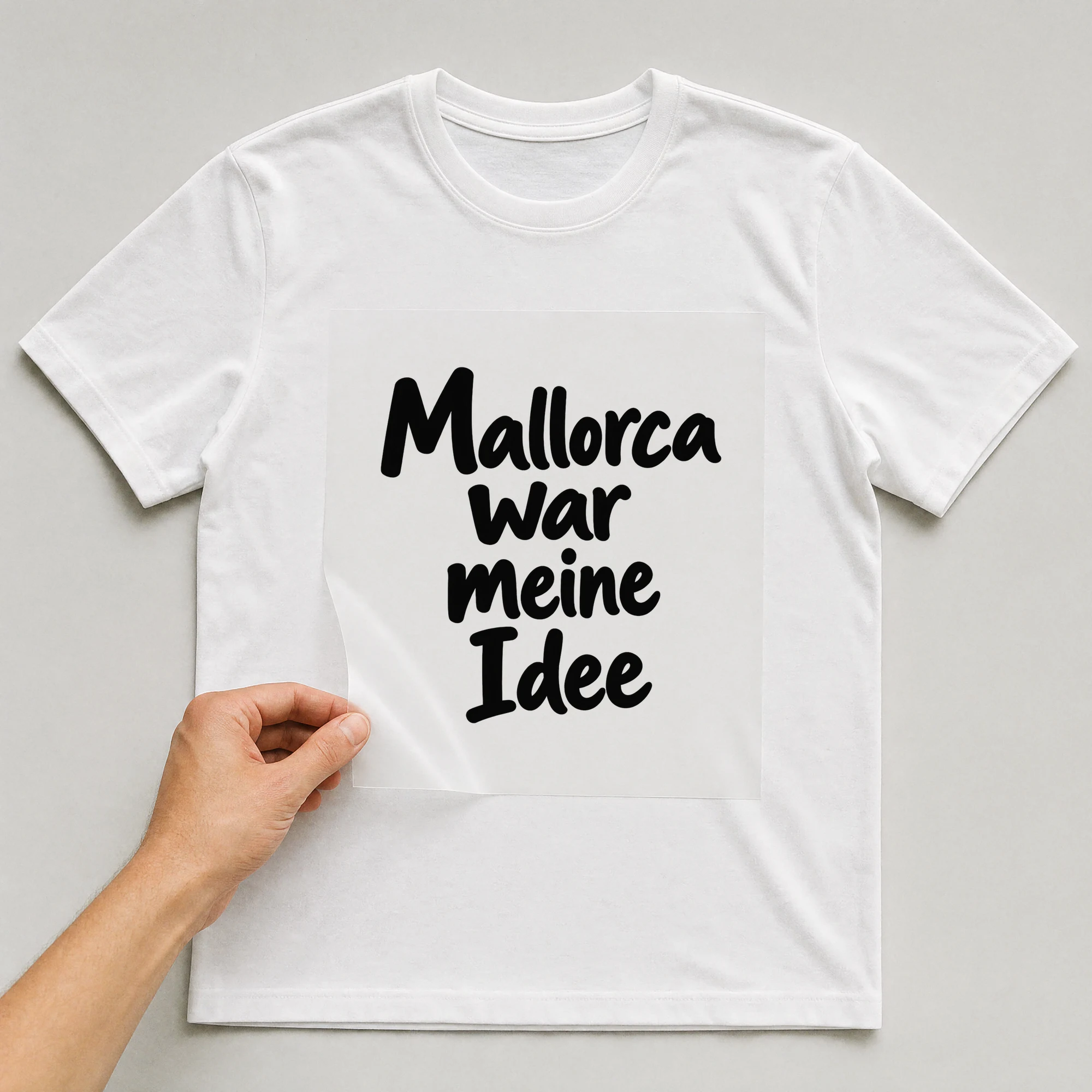 Bügelbild „Mallorca war meine Idee“ auf weißem T-Shirt, Folie wird aufgelegt