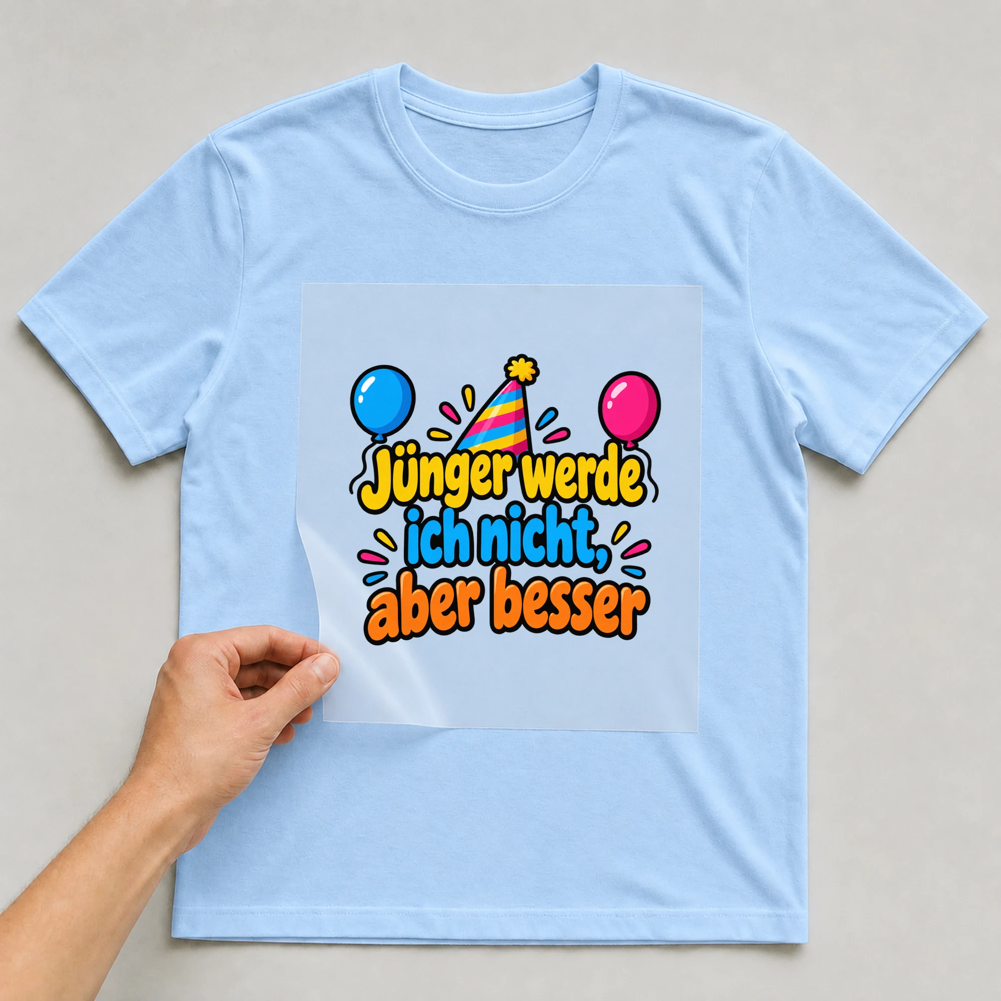 Bügelbild „Jünger werde ich nicht, aber besser“ auf babyblauem T-Shirt, Folie wird aufgelegt