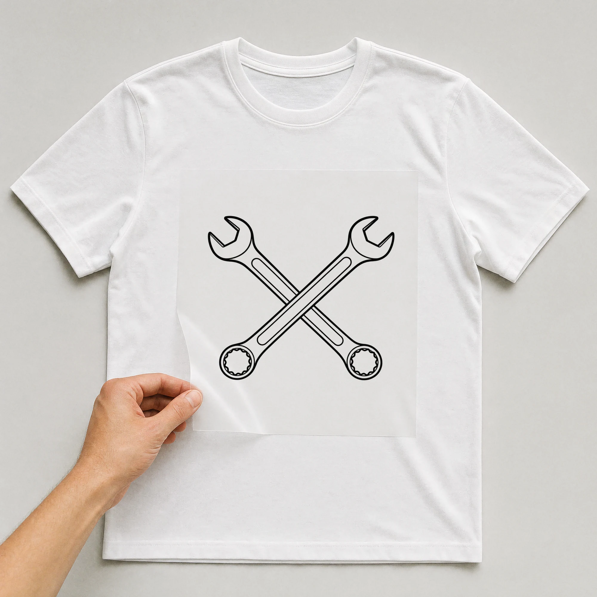 Bügelbild „Schraubenschlüssel“ auf weißem T-Shirt, Folie wird aufgelegt