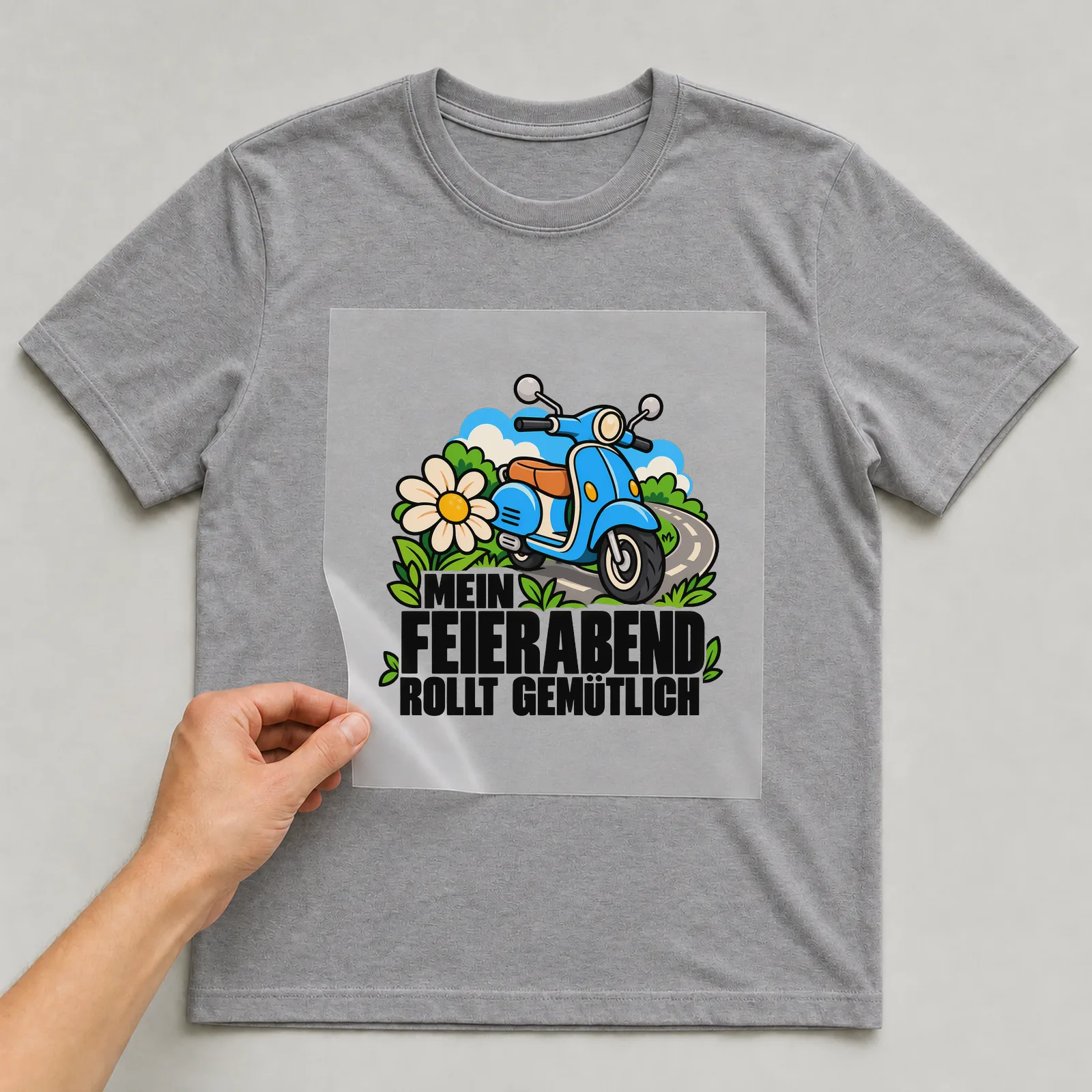 Bügelbild „Mein Feierabend rollt gemütlich“ auf grauem T-Shirt, Folie wird aufgelegt