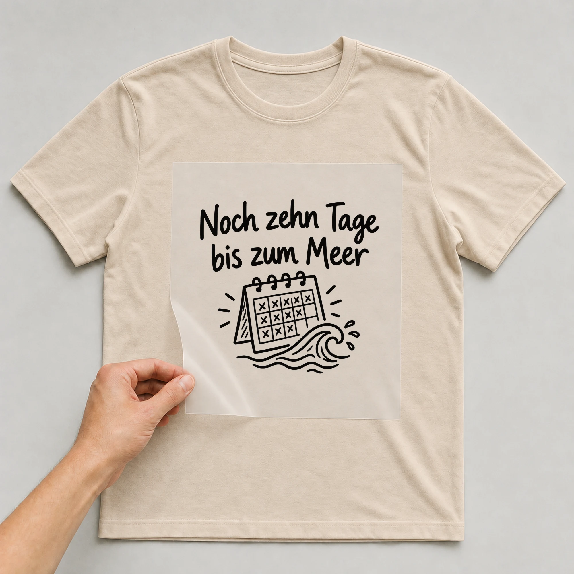 Bügelbild „Noch zehn Tage bis zum Meer“ auf beigem T-Shirt, Folie wird aufgelegt