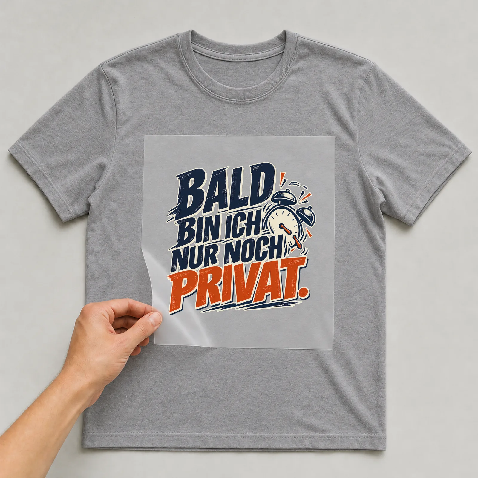 Bügelbild „Bald bin ich nur noch privat“ auf grauem T-Shirt, Folie wird aufgelegt