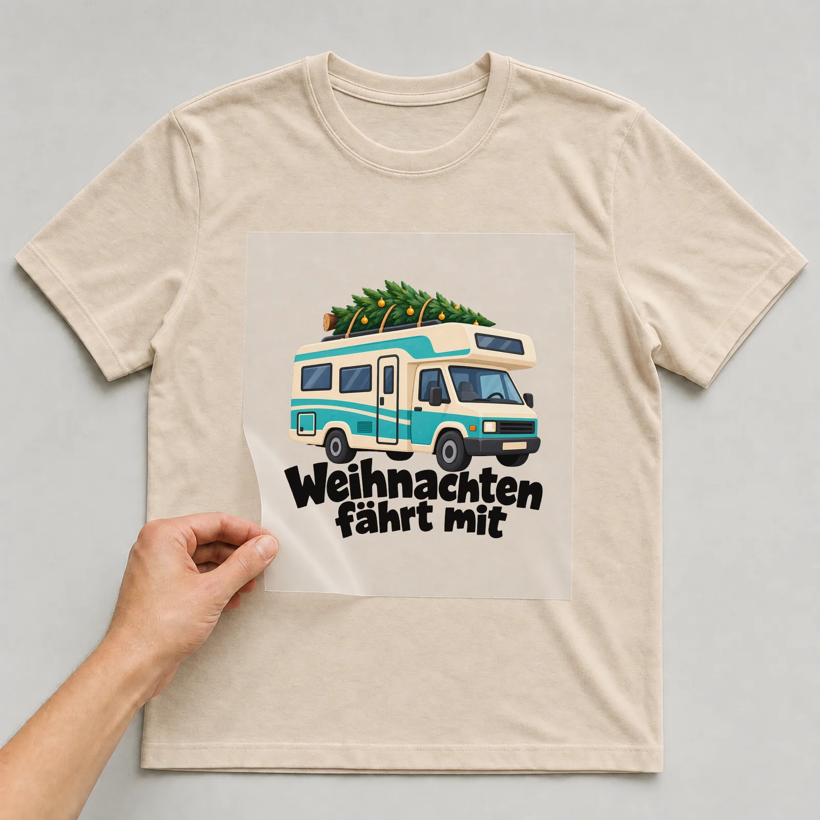 Bügelbild „Weihnachten fährt mit“ auf beigem T-Shirt, Folie wird aufgelegt