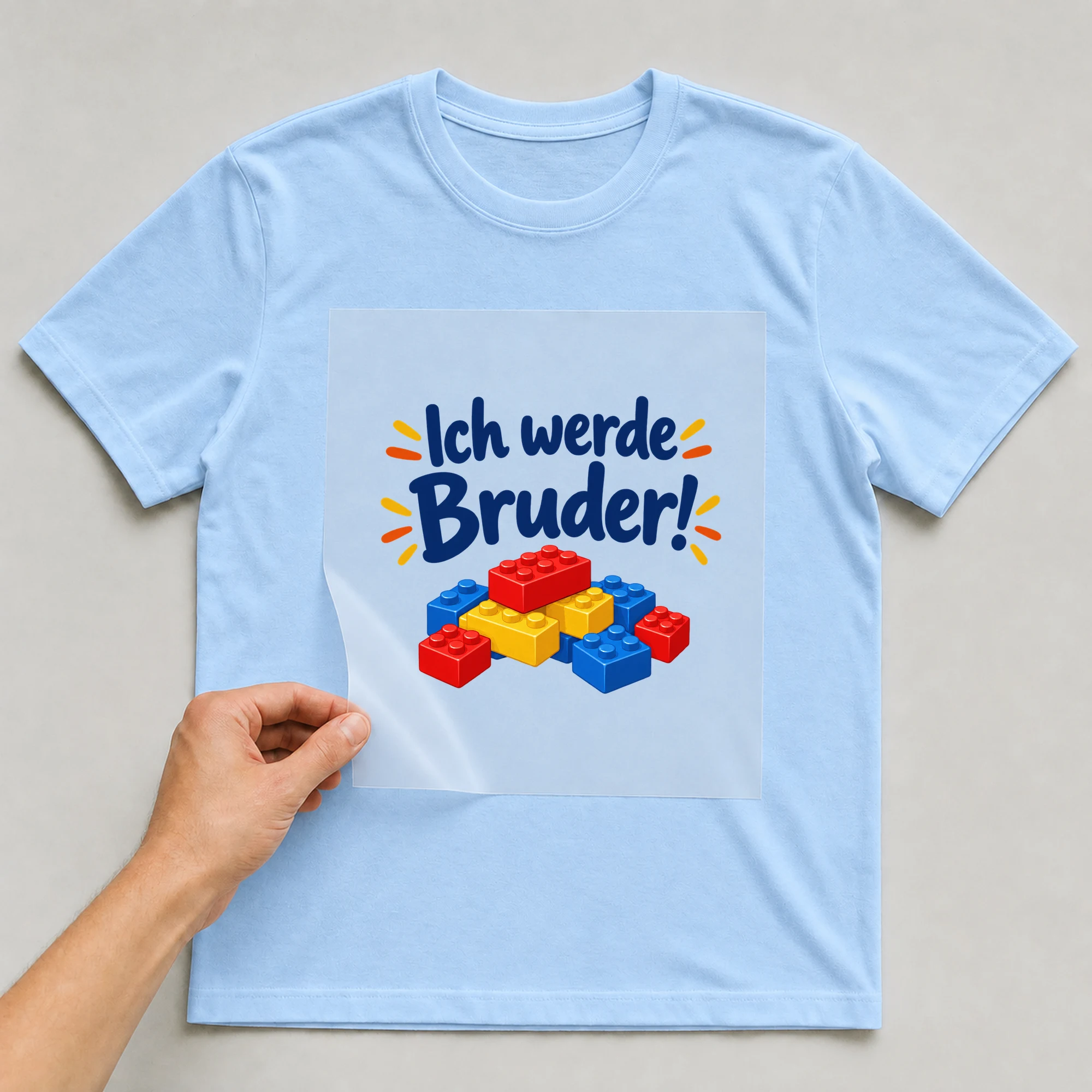 Bügelbild „Ich werde Bruder!“ auf babyblauem T-Shirt, Folie wird aufgelegt