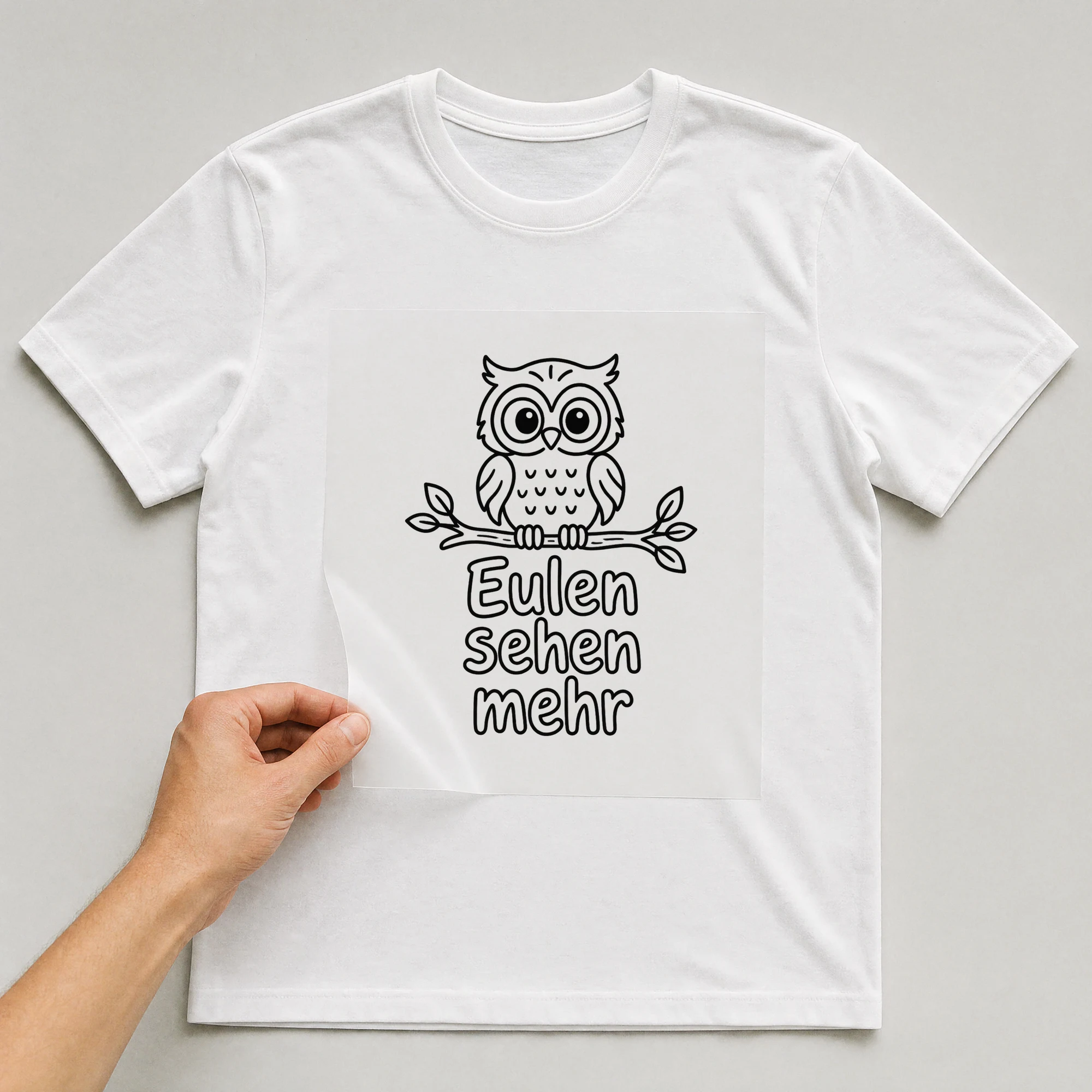Bügelbild „Eulen sehen mehr“ auf weißem T-Shirt, Folie wird aufgelegt