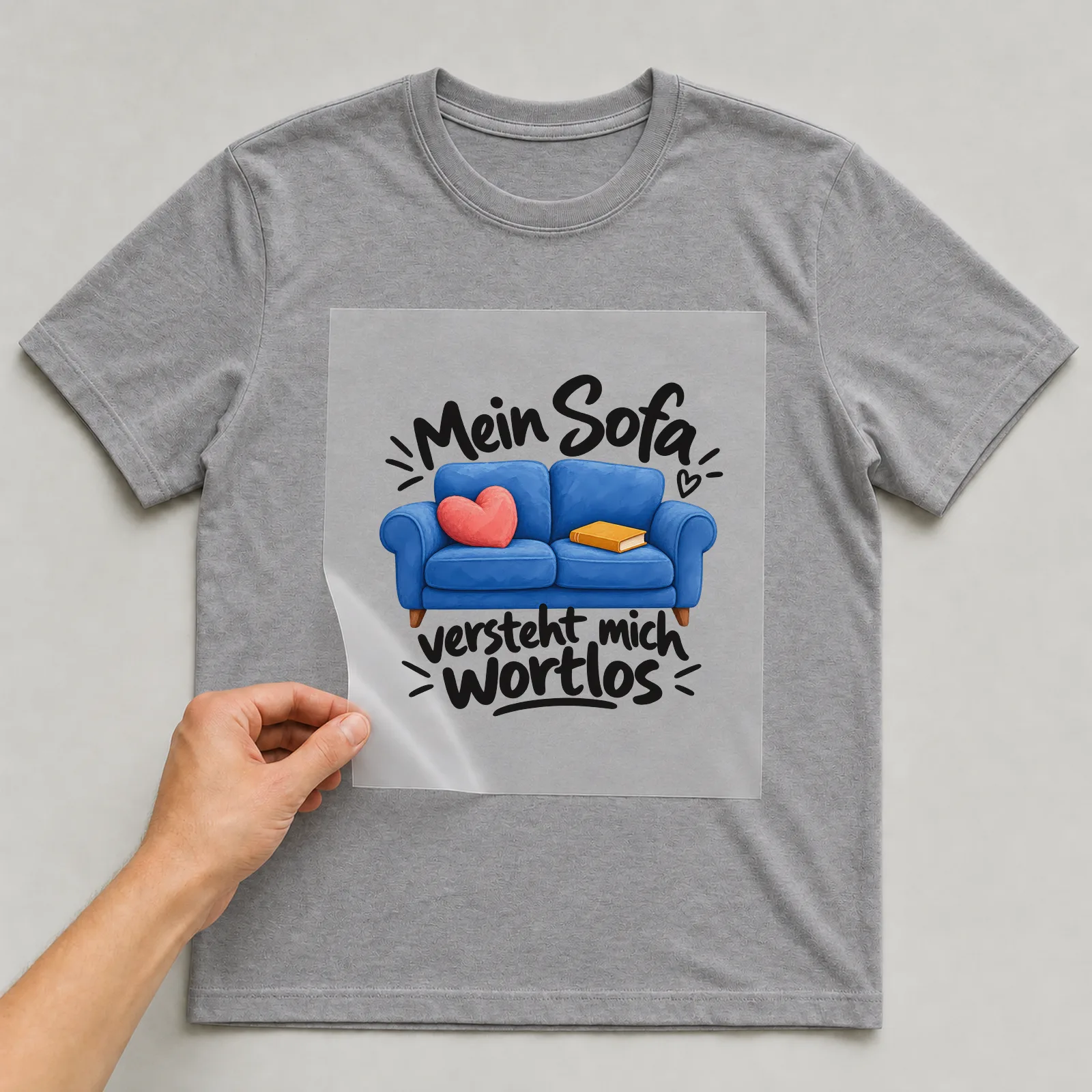 Bügelbild „Mein Sofa versteht mich wortlos“ auf grauem T-Shirt, Folie wird aufgelegt