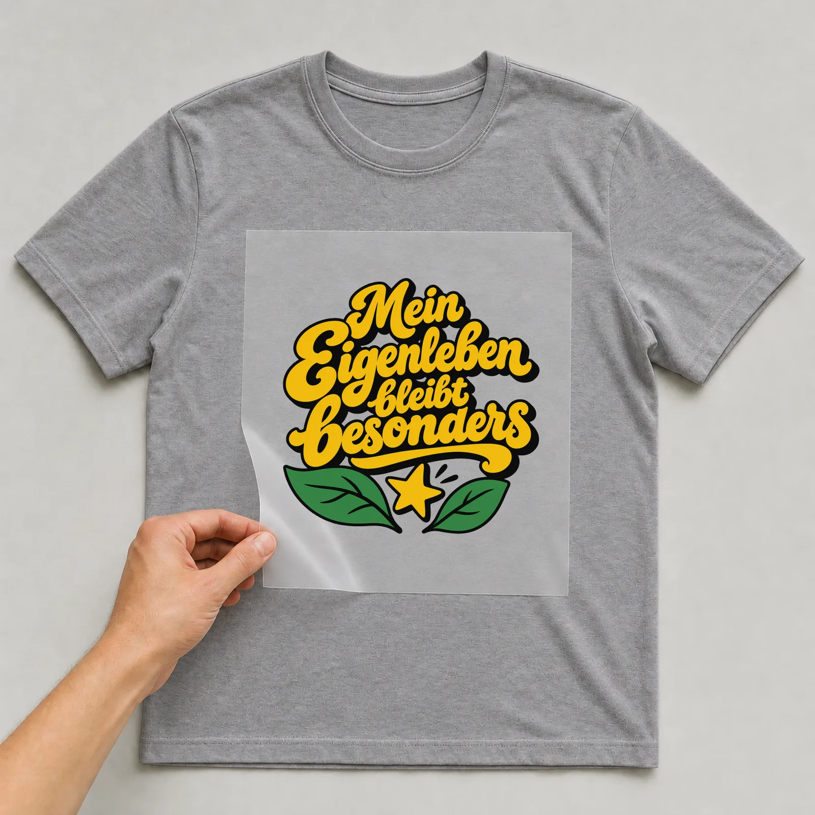Bügelbild „Mein Eigenleben bleibt besonders“ auf grauem T-Shirt, Folie wird aufgelegt