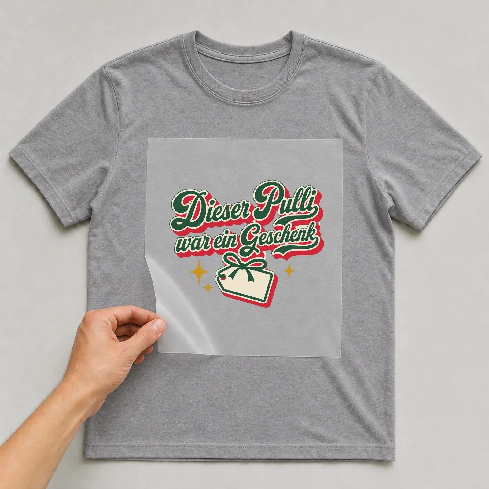 Bügelbild Dieser Pulli war ein Geschenk auf grauem T-Shirt, Folie wird aufgelegt