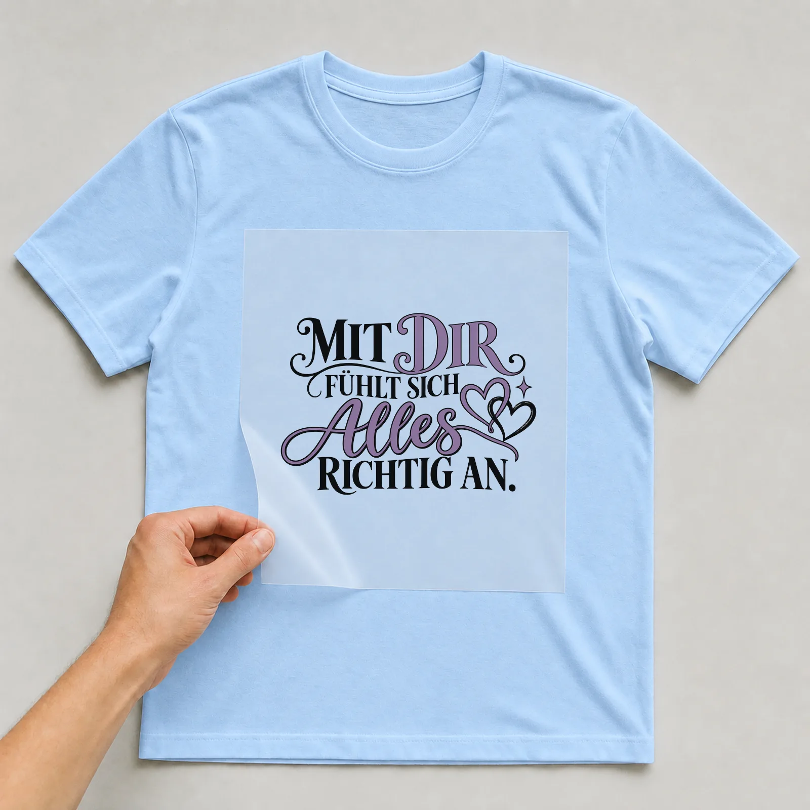 Bügelbild „Mit dir fühlt sich alles richtig an“ auf hellblauem T-Shirt, Folie wird aufgelegt