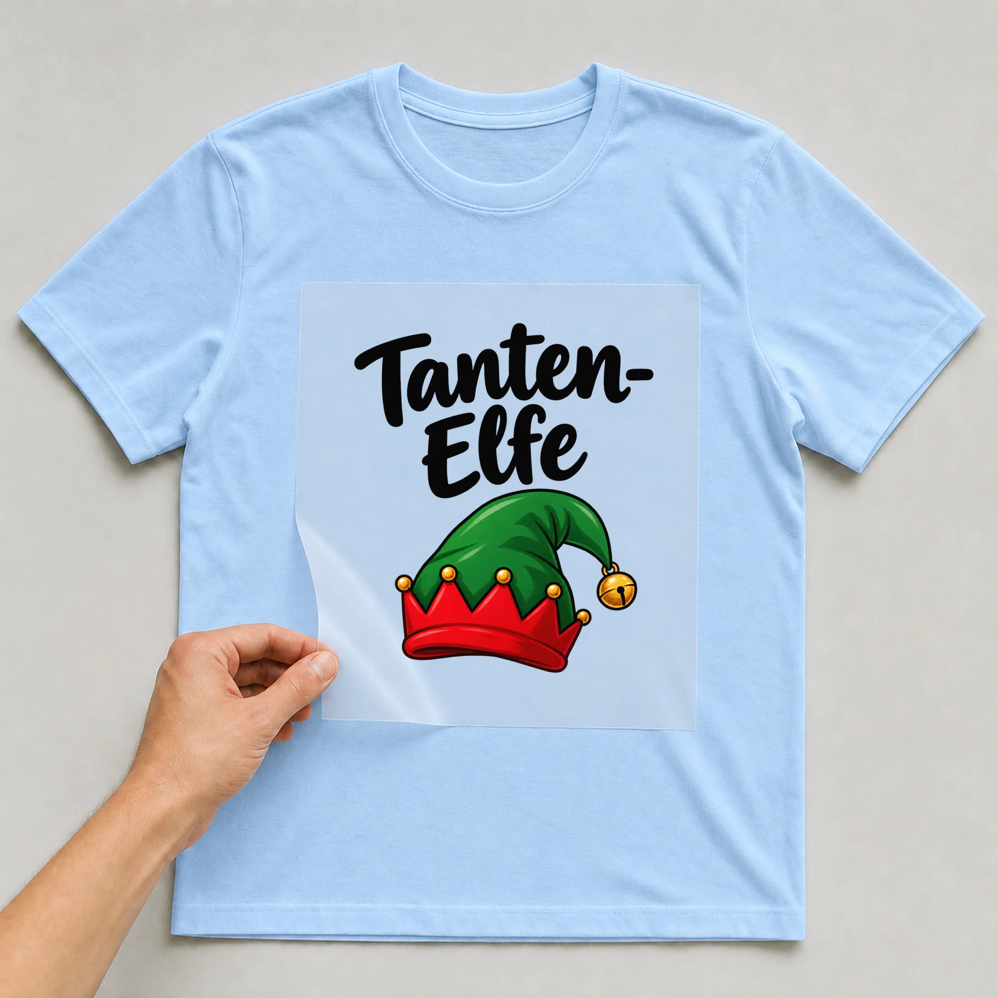 Bügelbild „Tanten-Elfe“ auf babyblauem T-Shirt, Folie wird aufgelegt