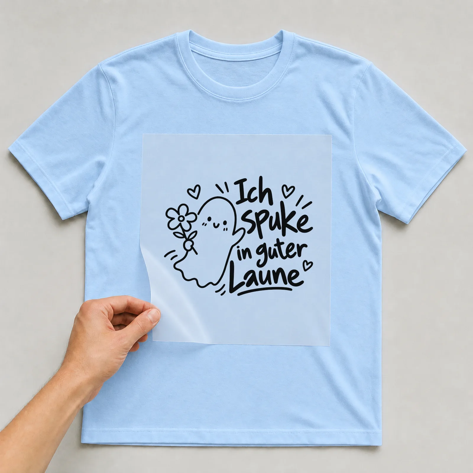 Bügelbild „Ich spuke in guter Laune“ auf hellblauem T-Shirt, Folie wird aufgelegt
