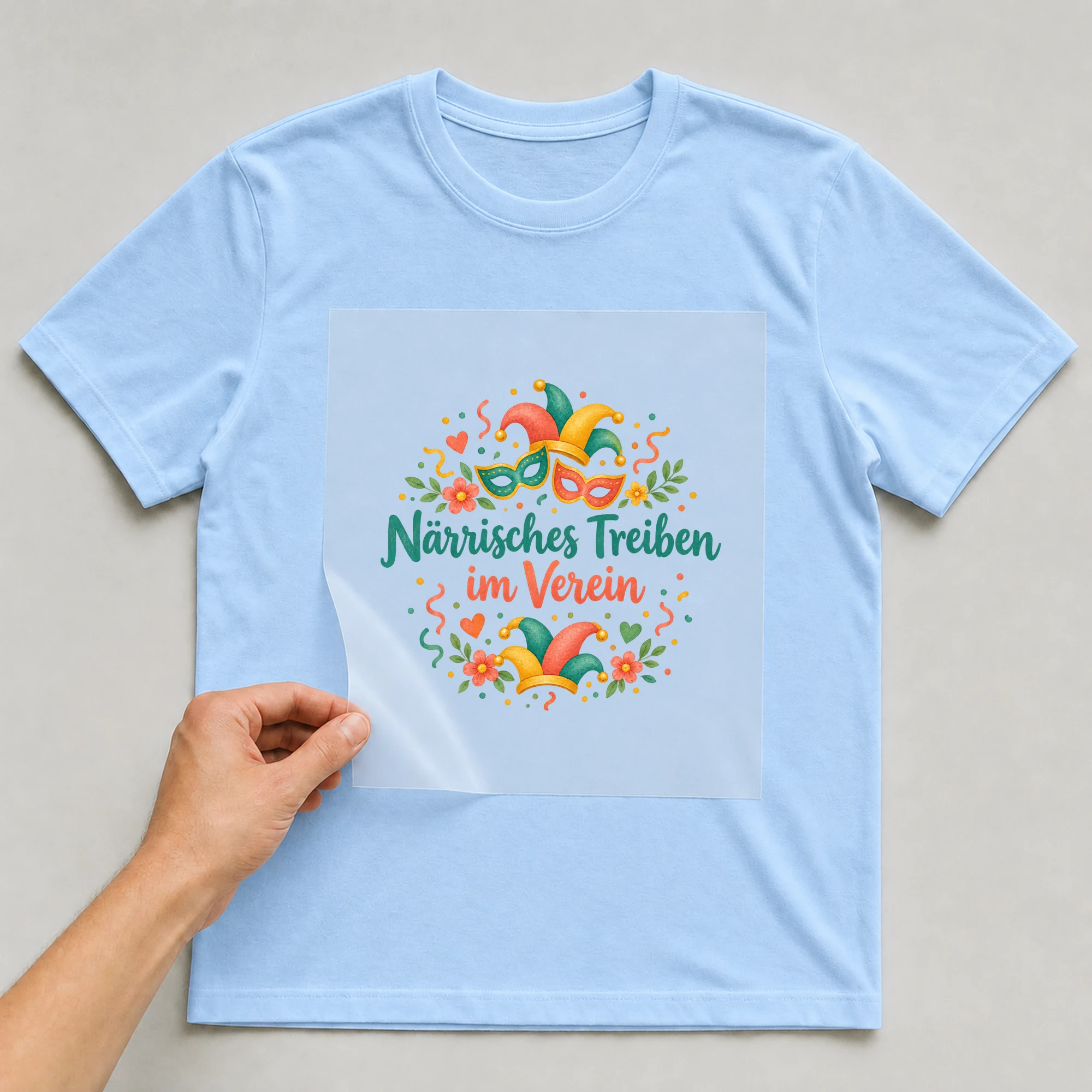 Bügelbild „Närrisches Treiben im Verein“ auf babyblauem T-Shirt, Folie wird aufgelegt
