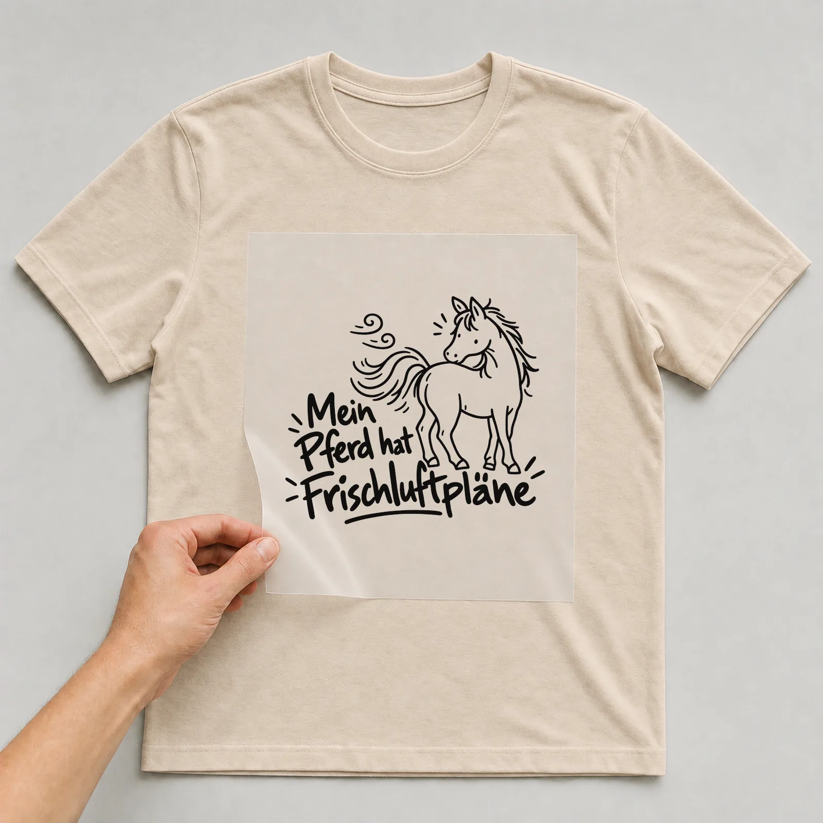 Bügelbild „Mein Pferd hat Frischluftpläne“ auf beigem T-Shirt, Folie wird aufgelegt