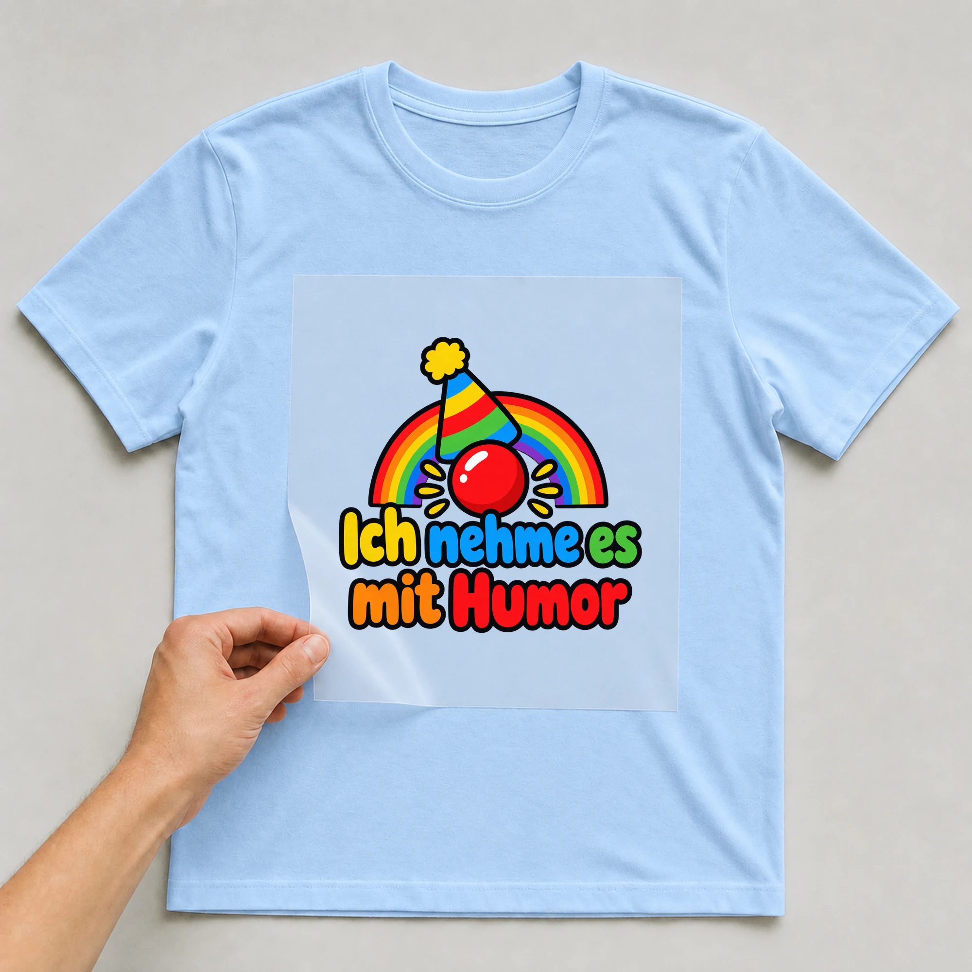 Bügelbild „Ich nehme es mit Humor“ auf babyblauem T-Shirt, Folie wird aufgelegt