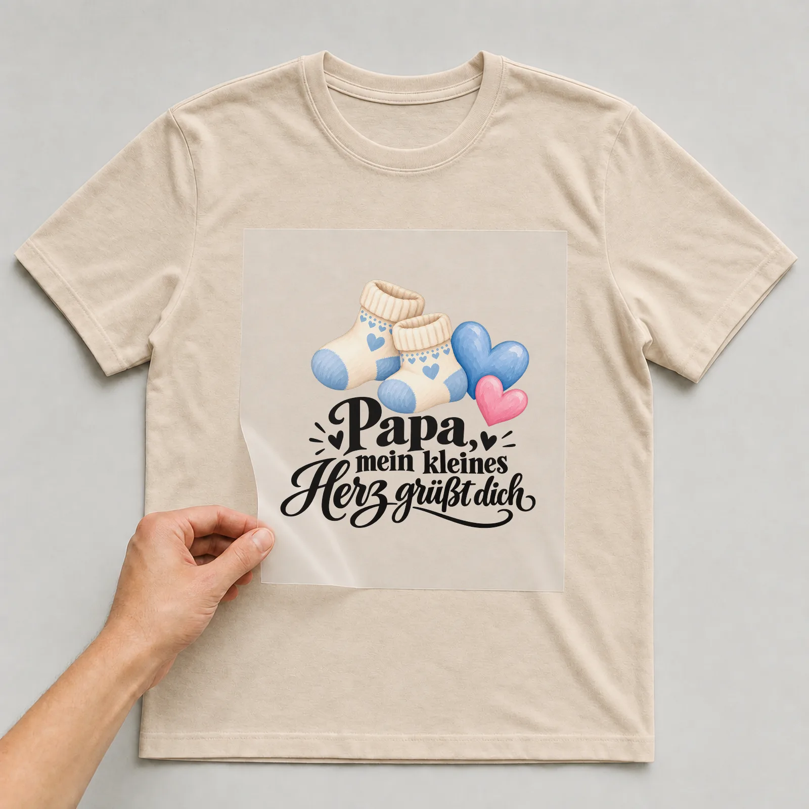 Bügelbild „Papa, mein kleines Herz grüßt dich“ auf beigem T-Shirt, Folie wird aufgelegt