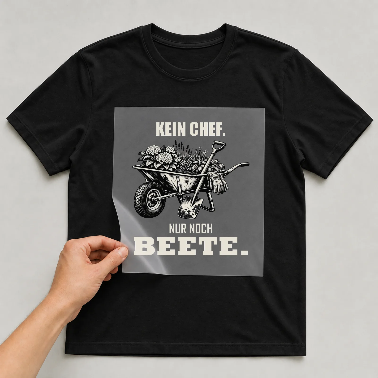 Bügelbild „Kein Chef. Nur noch Beete.“ auf schwarzem T-Shirt, Folie wird aufgelegt