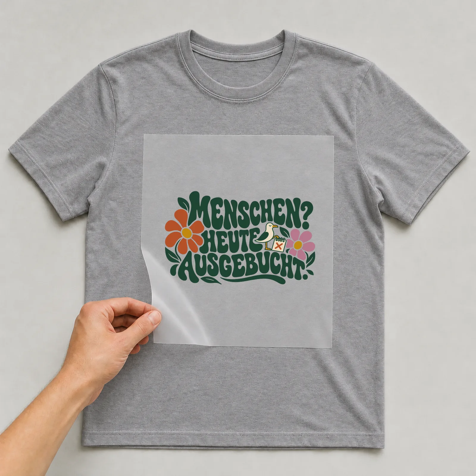 Bügelbild „Menschen? Heute ausgebucht.“ auf grauem T-Shirt, Folie wird aufgelegt