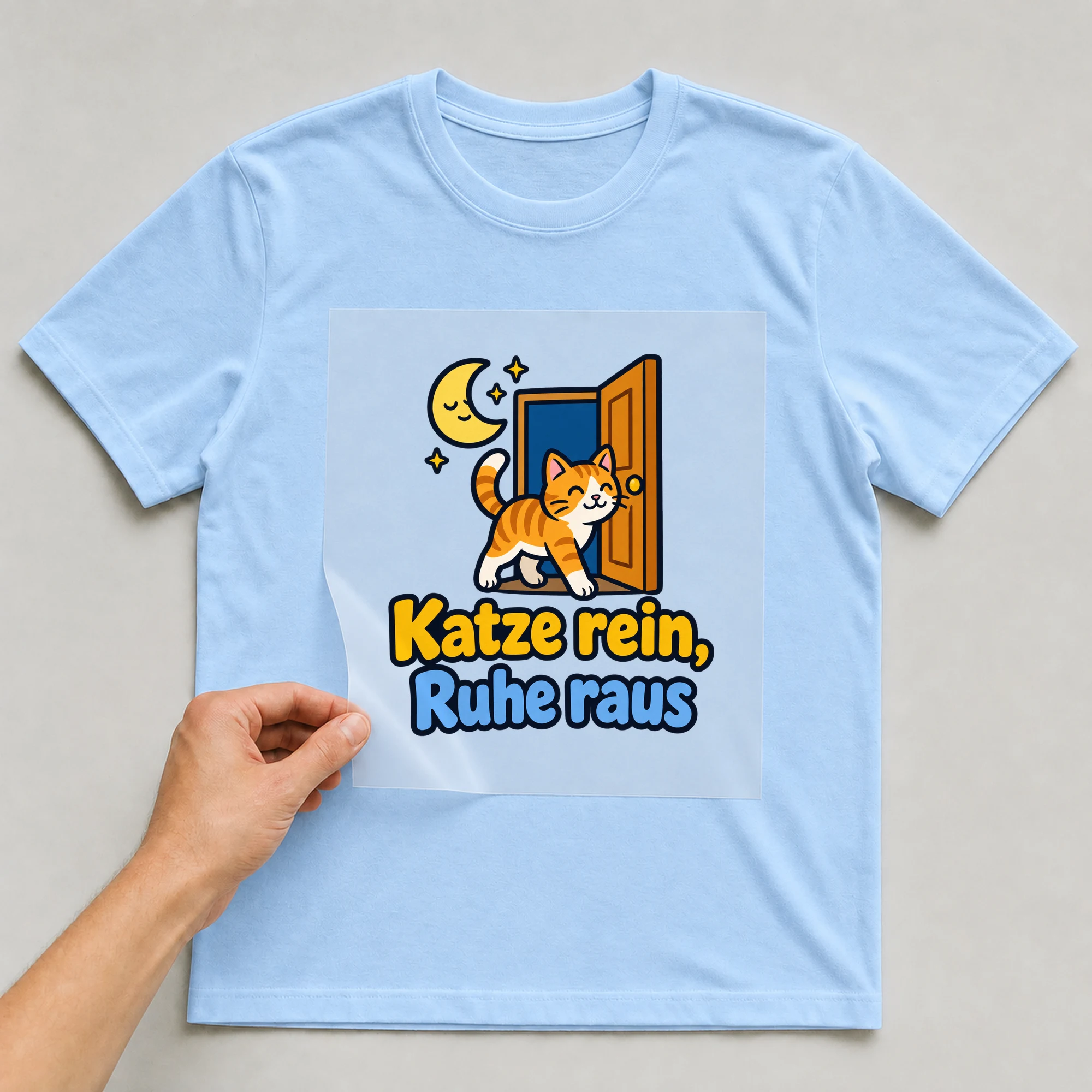 Bügelbild „Katze rein, Ruhe raus“ auf babyblauem T-Shirt, Folie wird aufgelegt
