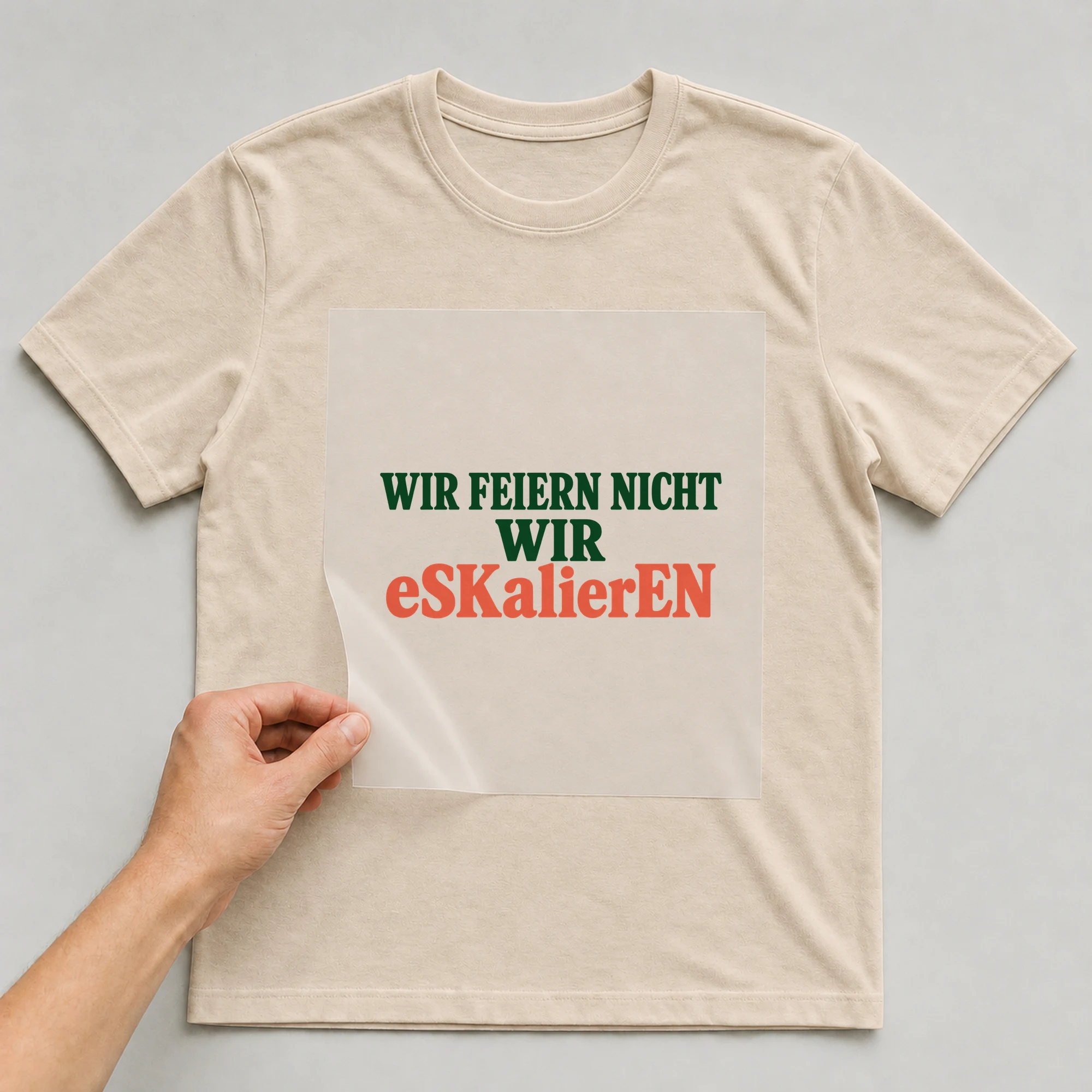Bügelbild „WIR FEIERN NICHT WIR eSKalierEN“ auf beigem T-Shirt, Folie wird aufgelegt