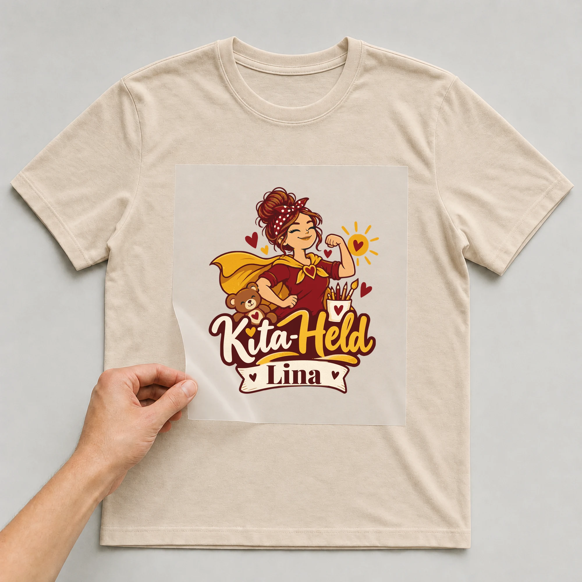 Bügelbild Kita-Held mit Name auf beigem T-Shirt, Folie wird aufgelegt