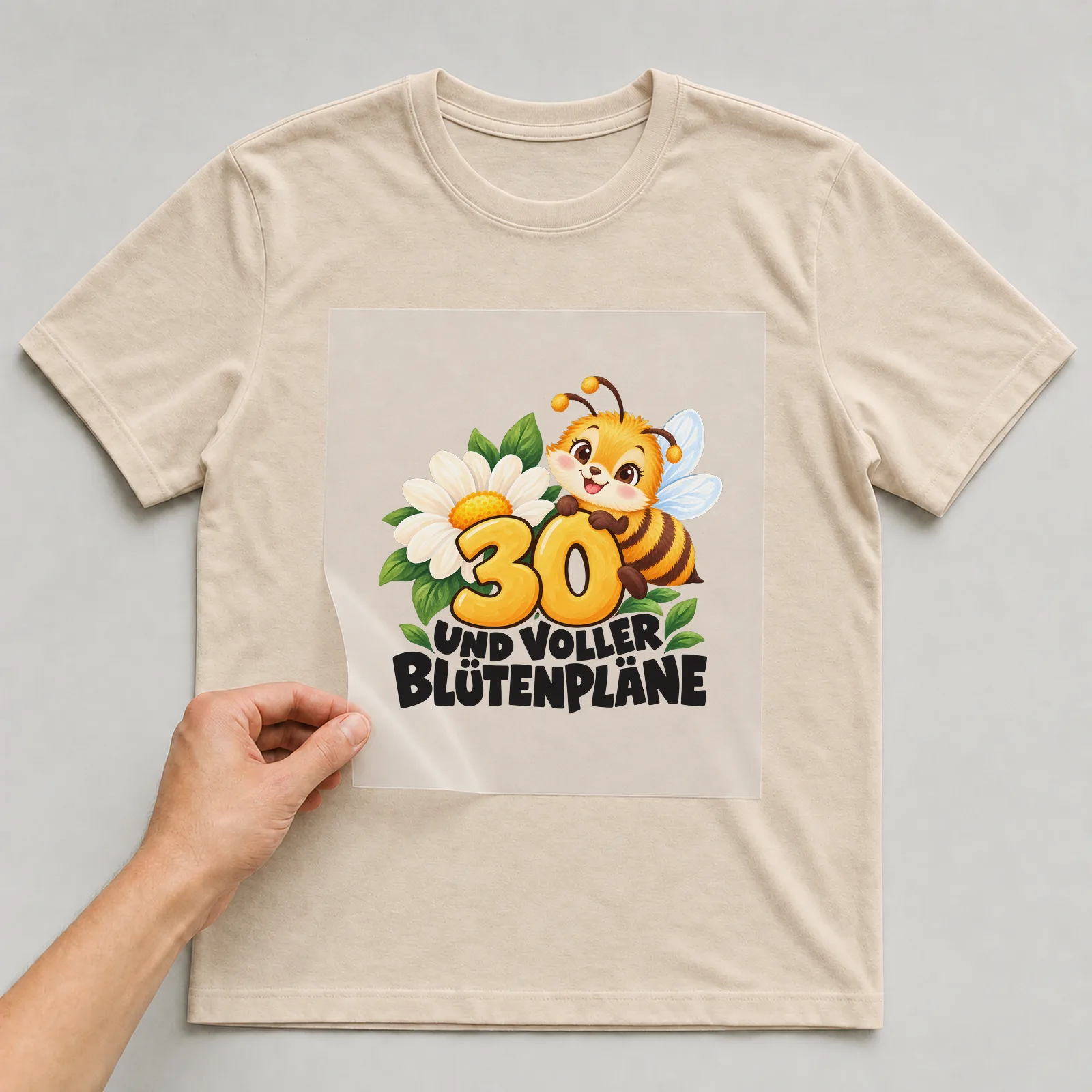 Bügelbild „30 Und voller Blütenpläne“ auf beigem T-Shirt, Folie wird aufgelegt
