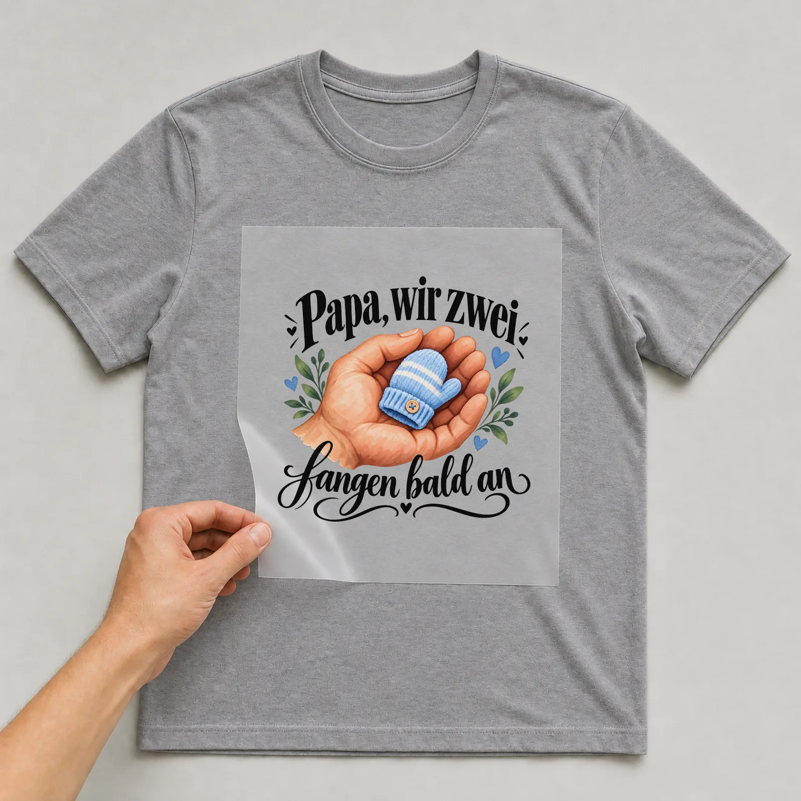 Bügelbild „Papa, wir zwei fangen bald an“ auf grauem T-Shirt, Folie wird aufgelegt