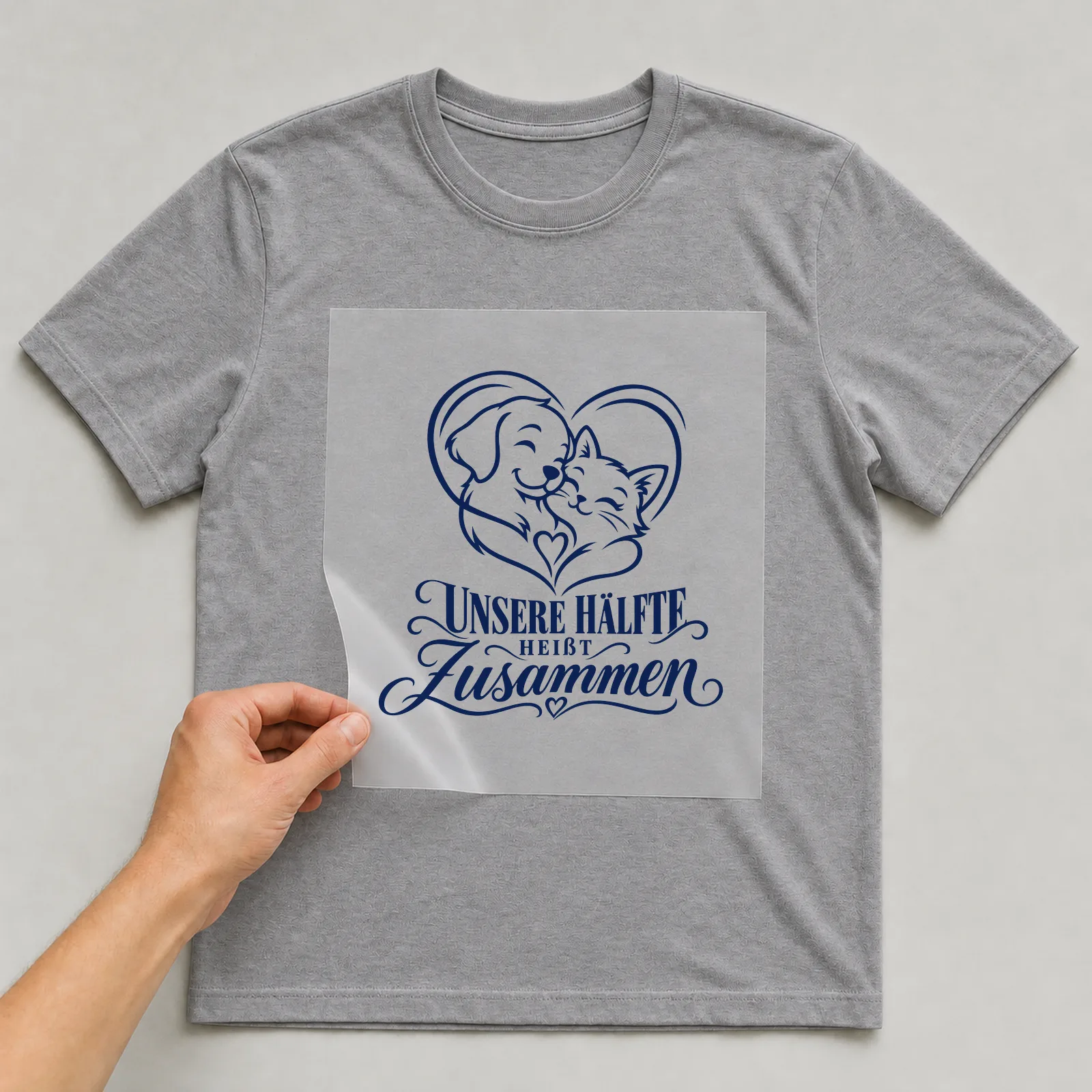 Bügelbild „Unsere Hälfte heißt Zusammen“ auf grauem T-Shirt, Folie wird aufgelegt