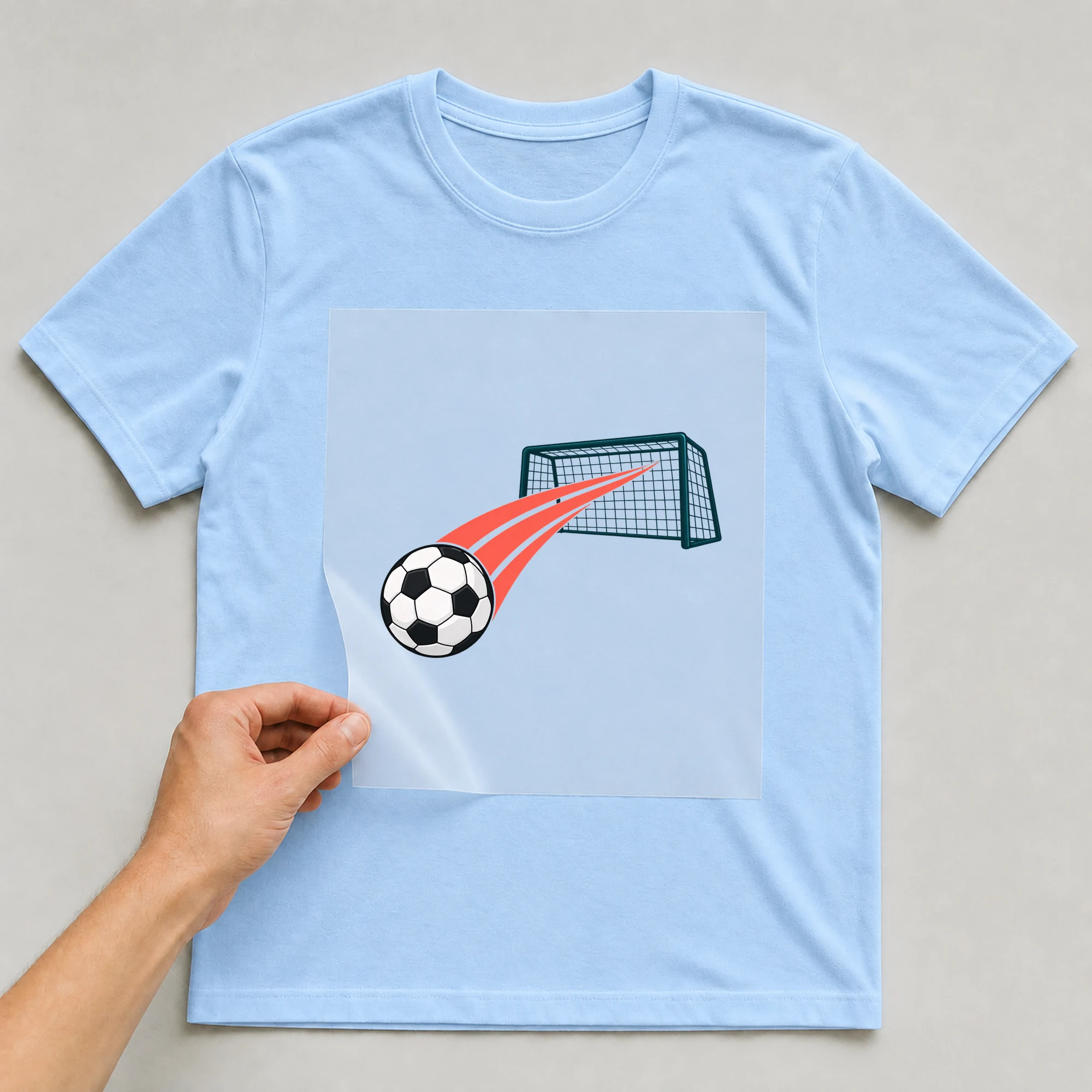 Bügelbild „Fußball Collage“ auf babyblauem T-Shirt, Folie wird aufgelegt
