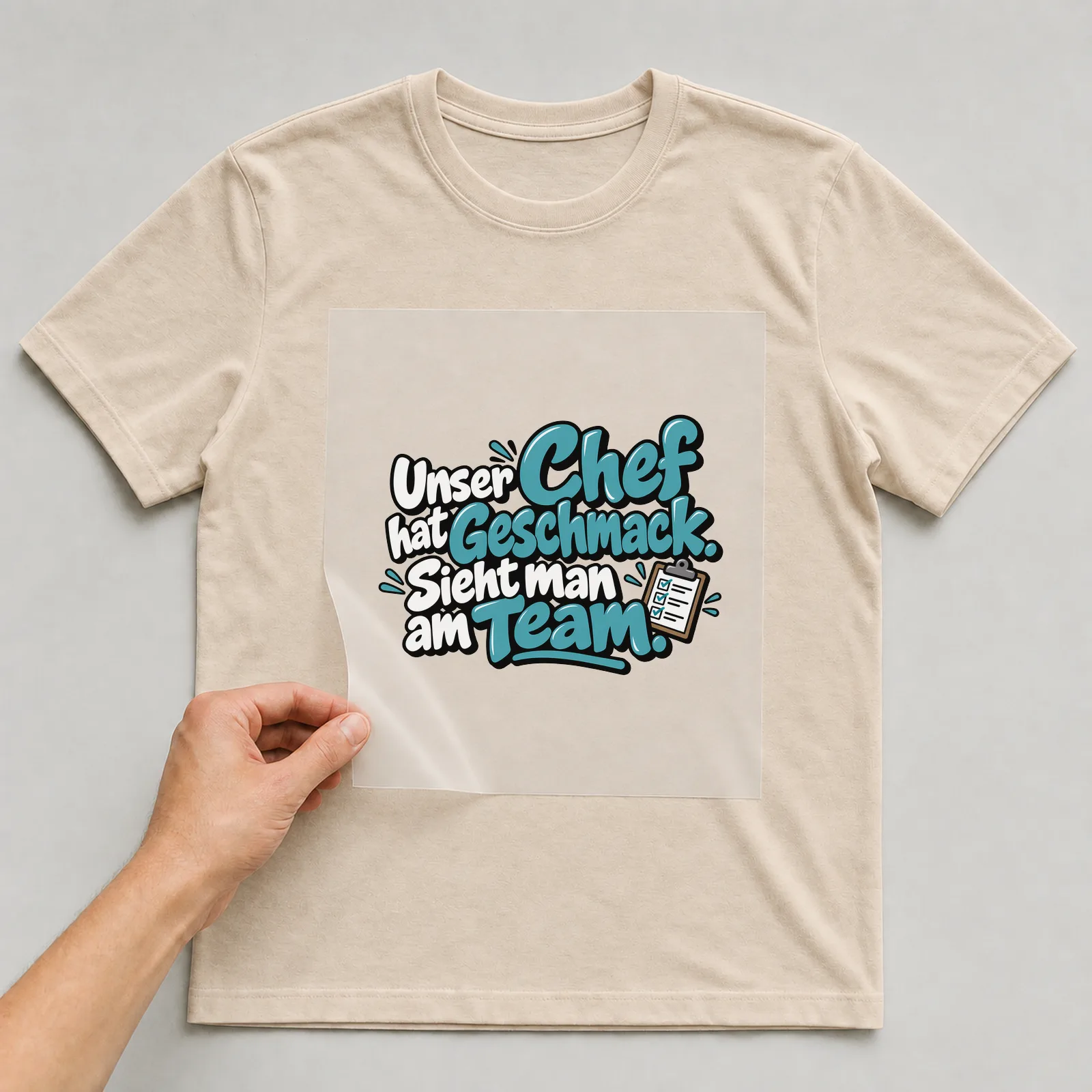 Bügelbild „Unser Chef hat Geschmack. Sieht man am Team.“ auf beigem T-Shirt, Folie wird aufgelegt