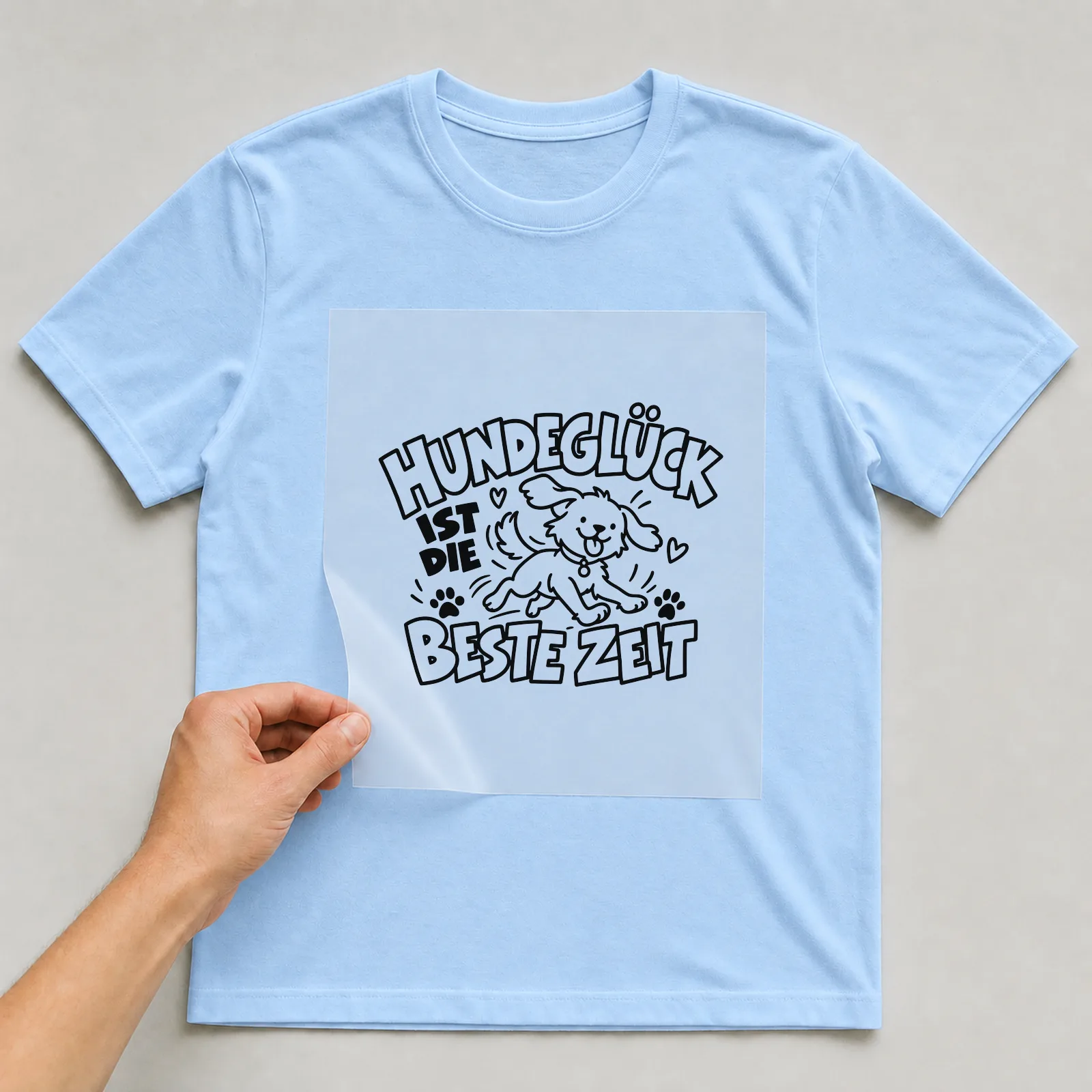 Bügelbild „Hundeglück ist die beste Zeit“ auf hellblauem T-Shirt, Folie wird aufgelegt