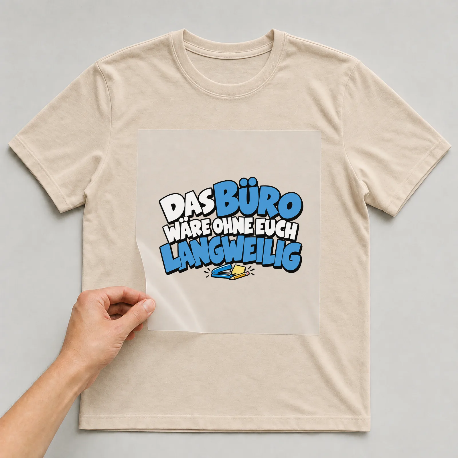 Bügelbild „Das Büro wäre ohne euch langweilig“ auf beigem T-Shirt, Folie wird aufgelegt