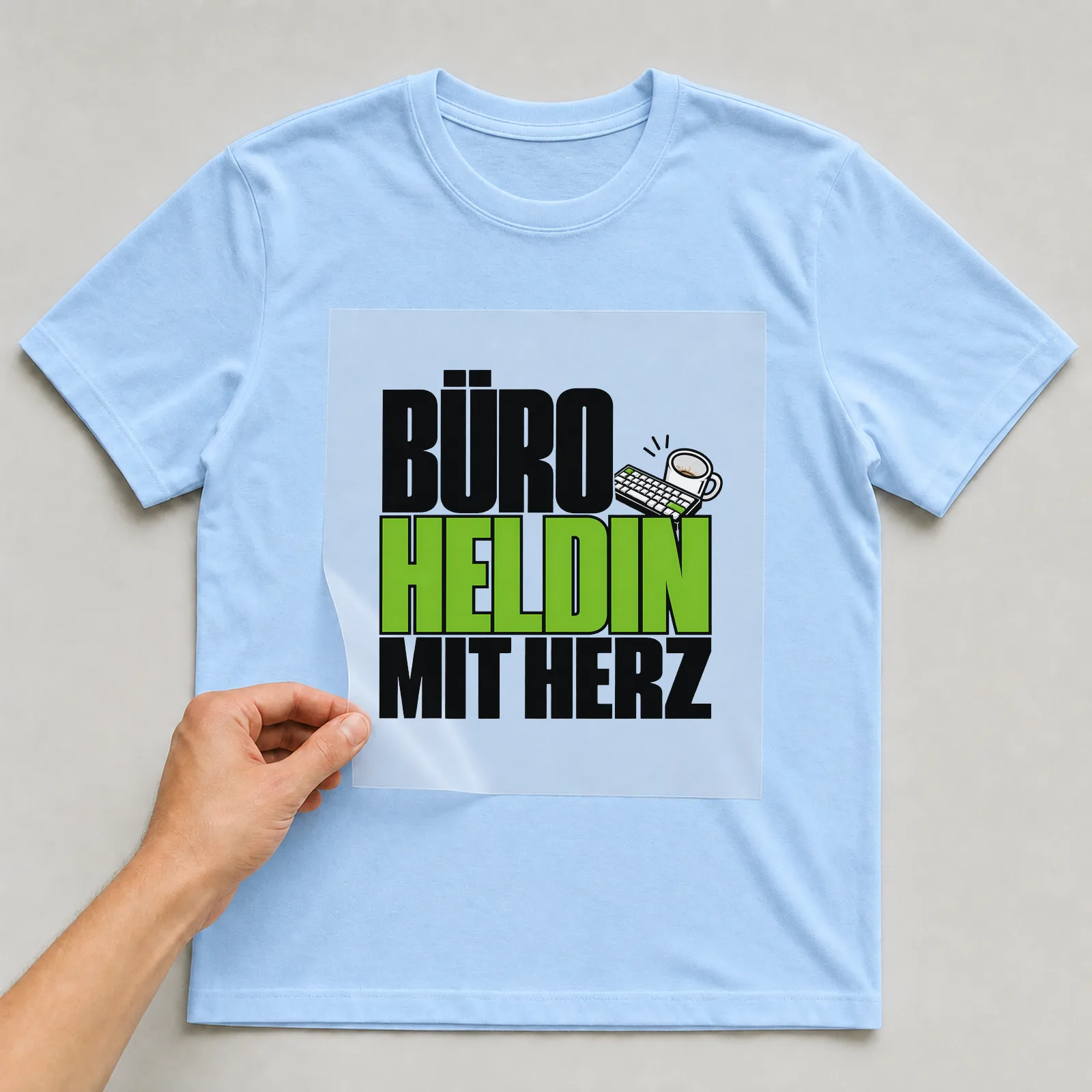 Bügelbild „Büroheldin mit Herz“ auf hellblauem T-Shirt, Folie wird aufgelegt
