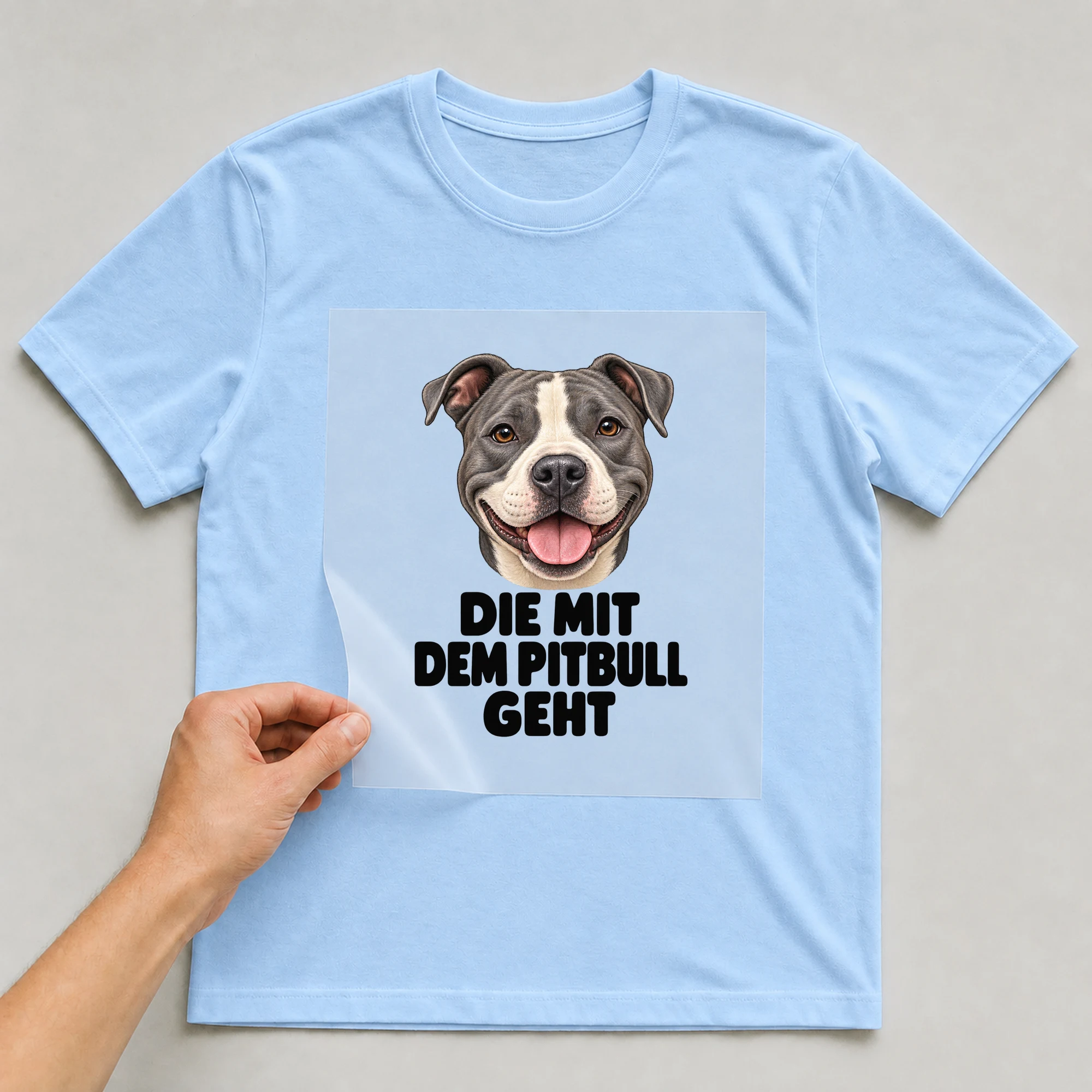 Bügelbild „Die mit dem Pitbull geht“ auf babyblauem T-Shirt, Folie wird aufgelegt