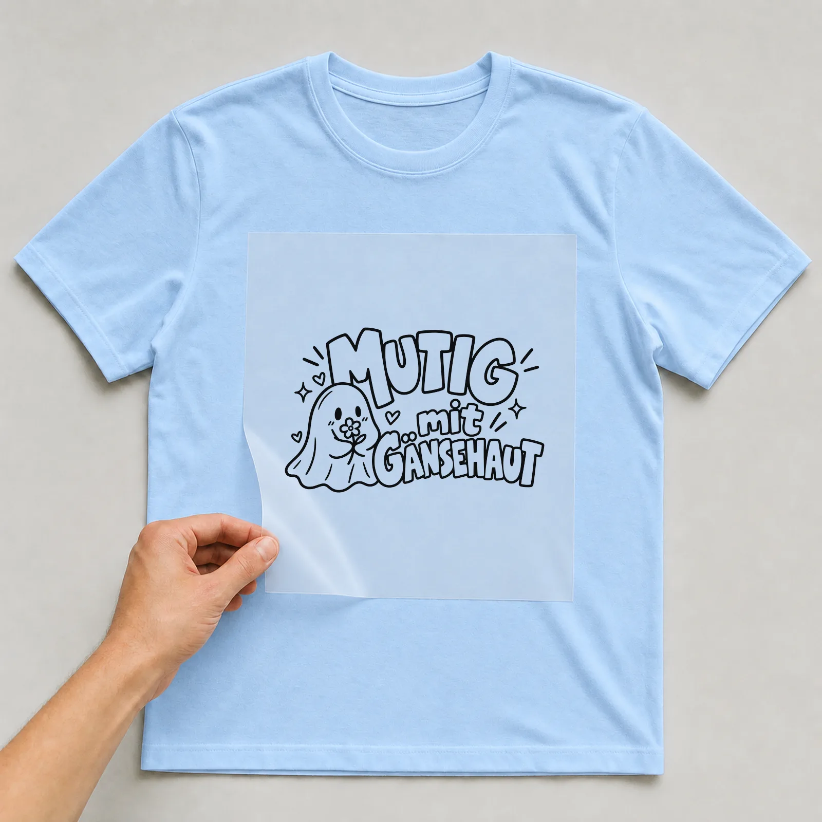 Bügelbild „Mutig mit Gänsehaut“ auf hellblauem T-Shirt, Folie wird aufgelegt