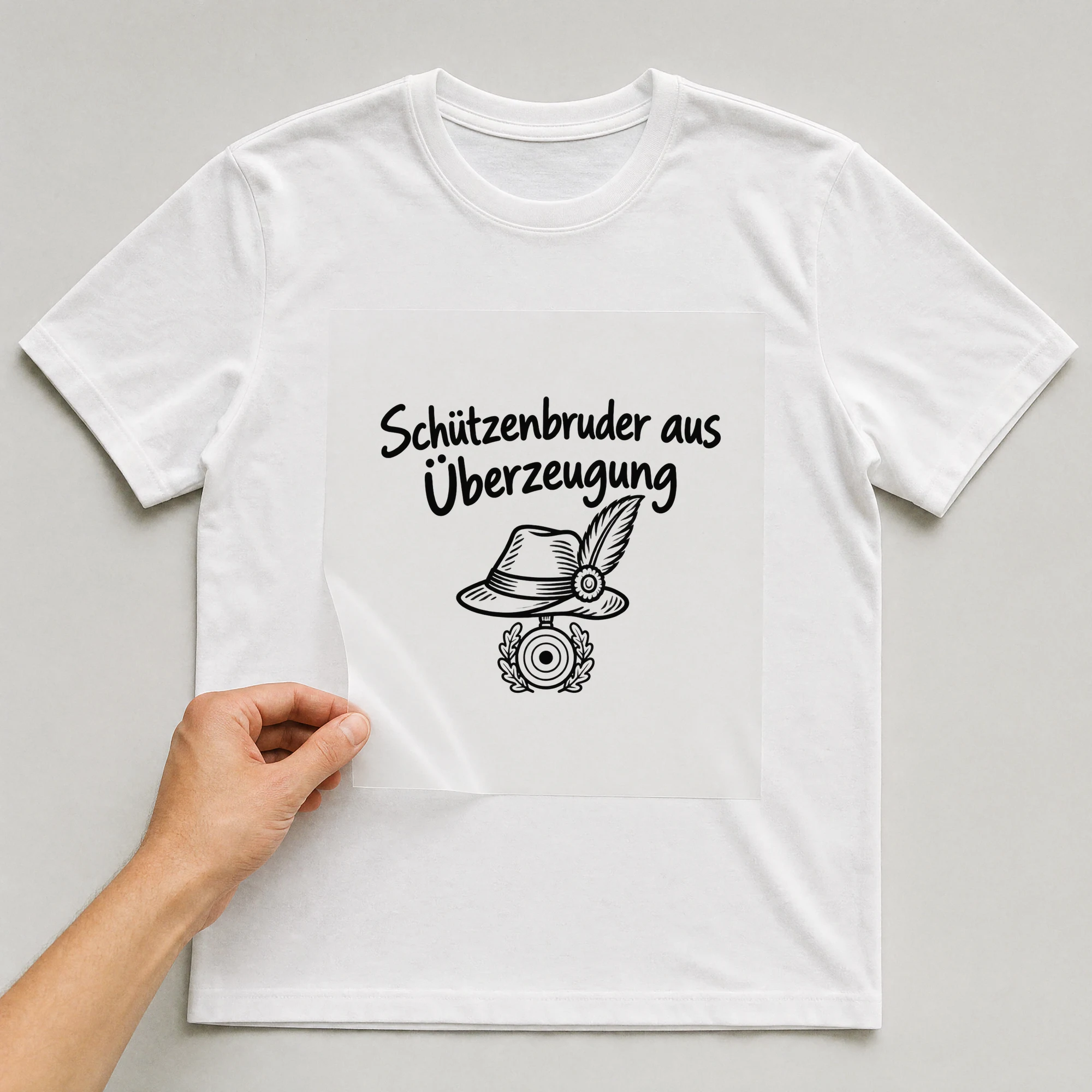 Bügelbild „Schützenbruder aus Überzeugung“ auf weißem T-Shirt, Folie wird aufgelegt