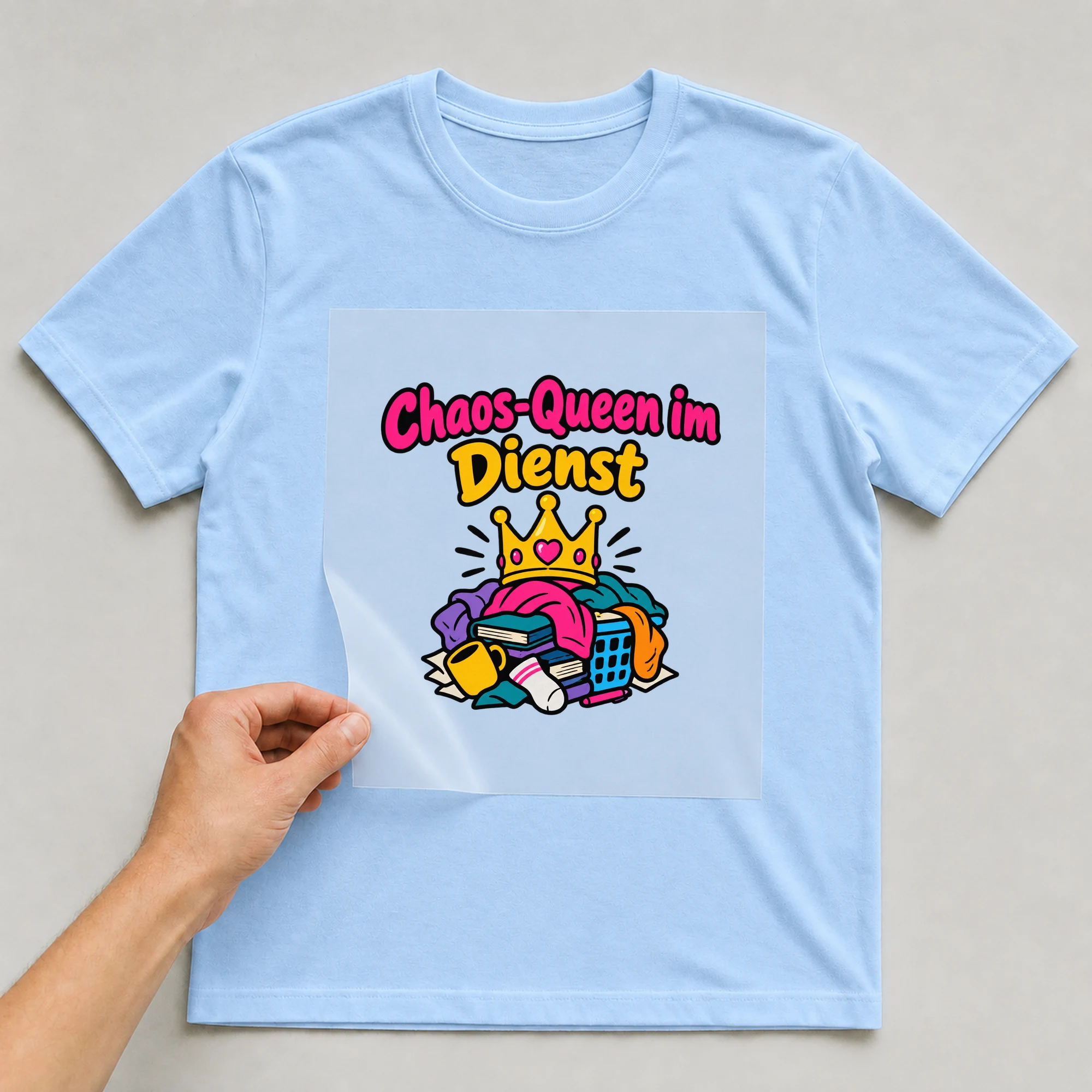 Bügelbild „Chaos-Queen im Dienst“ auf babyblauem T-Shirt, Folie wird aufgelegt