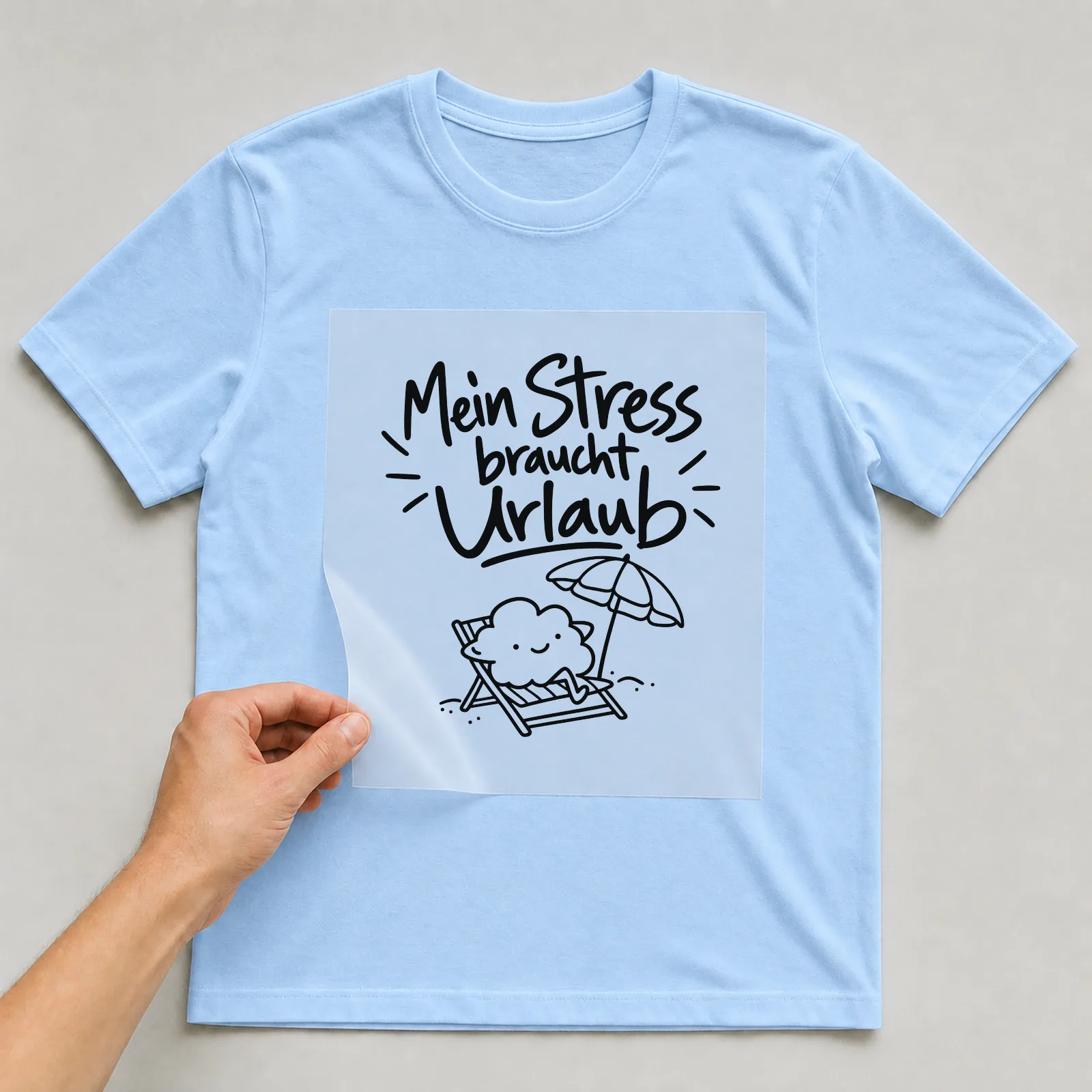 Bügelbild „Mein Stress braucht Urlaub“ auf hellblauem T-Shirt, Folie wird aufgelegt